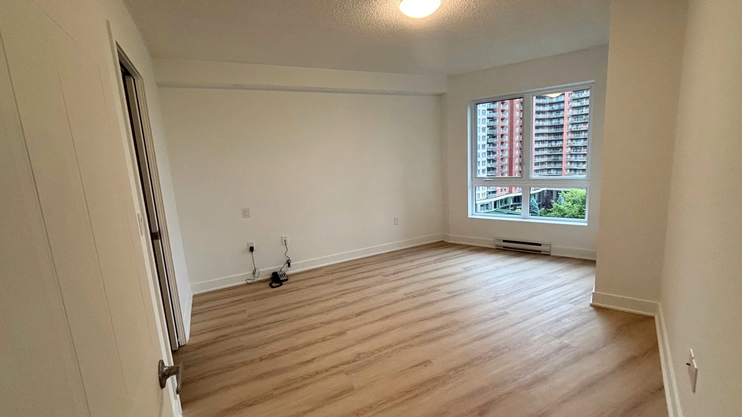 Chambre fraîchement repeinte dans un condo à Laval, plancher de bois et grande fenêtre