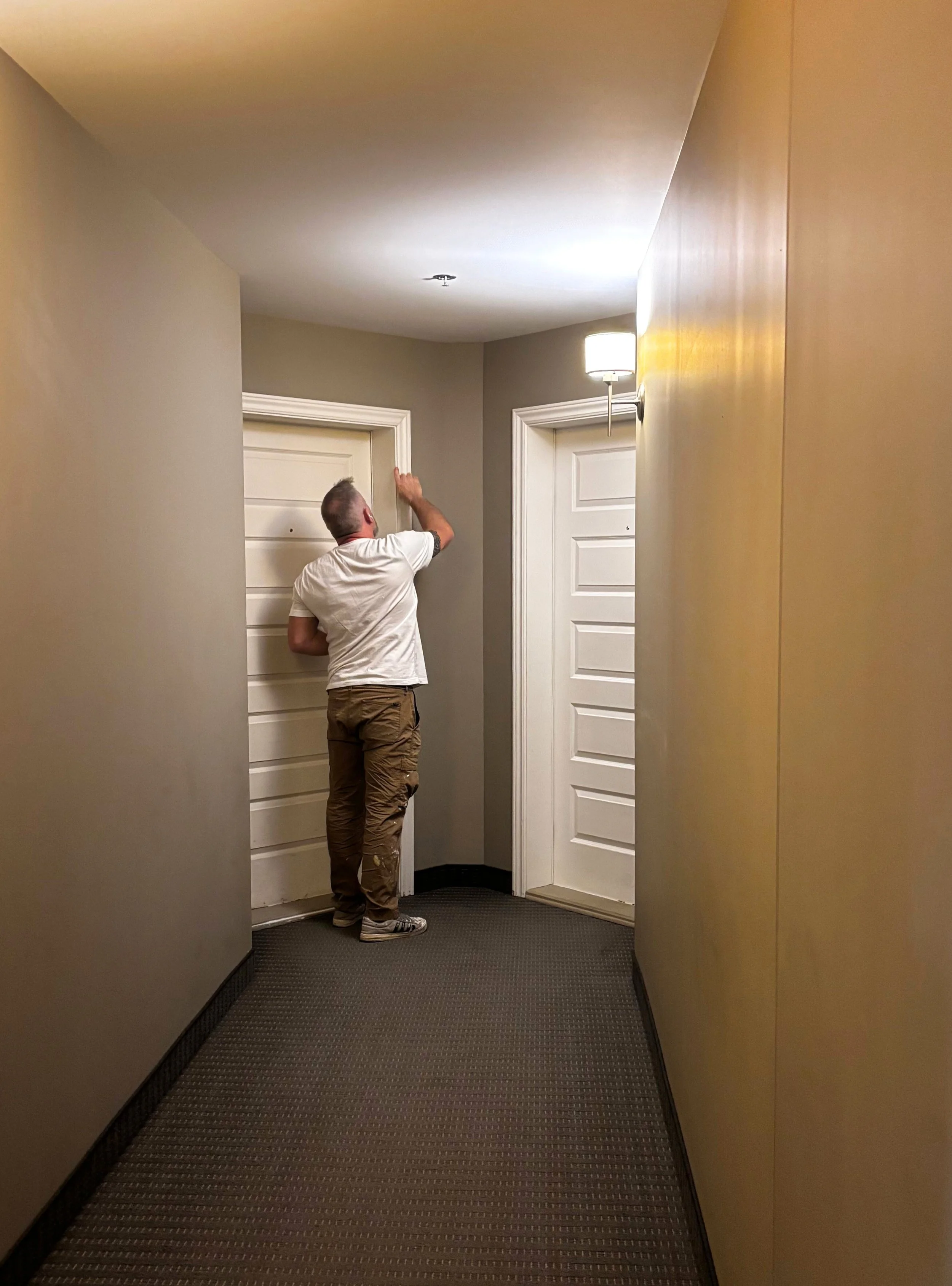 Patrick Jacob peignant une porte d'appartement dans un corridor de l'immeuble Des Ruisseaux V à Laval