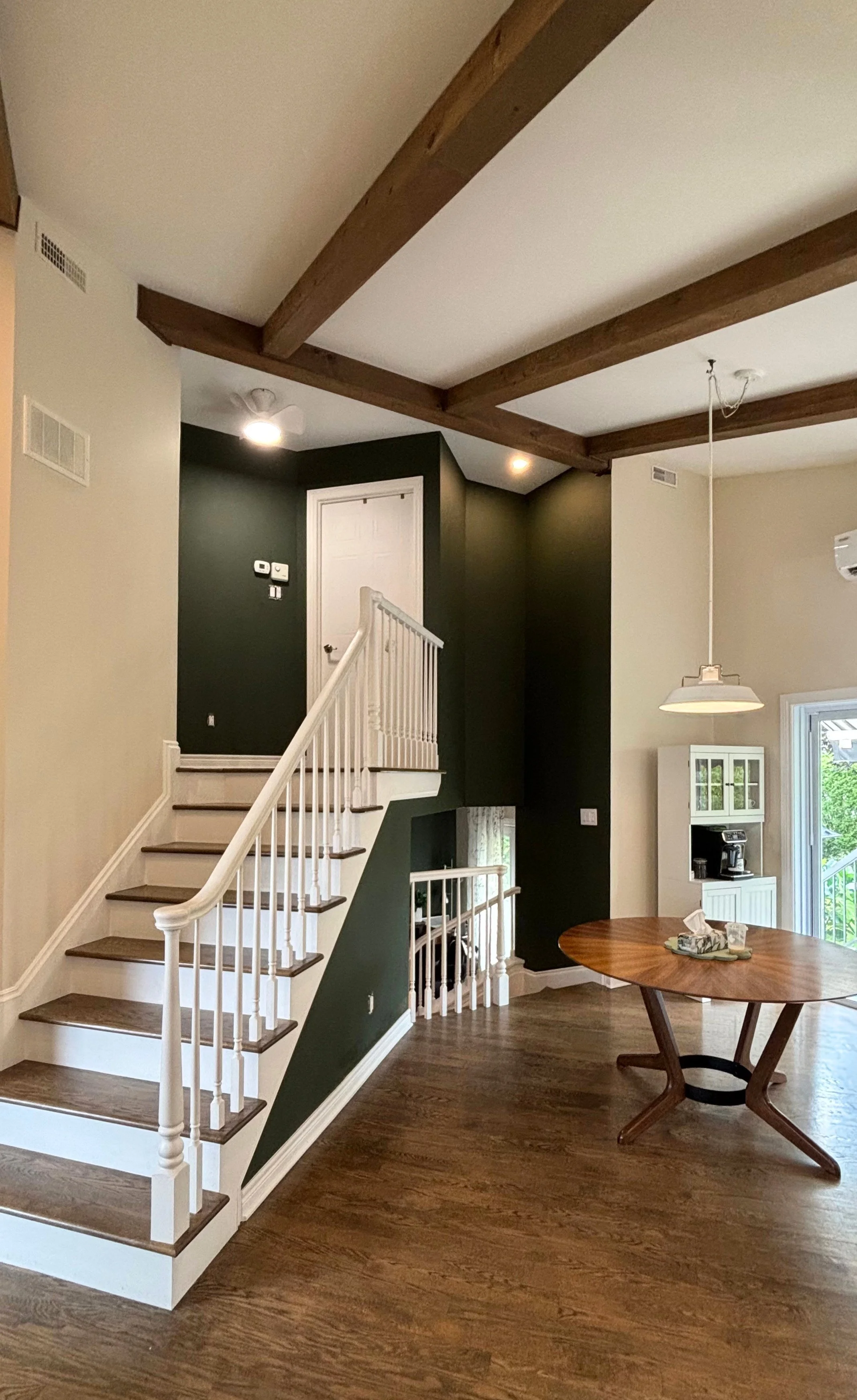 Escalier à rampe blanche longeant un mur d'accent peint en Vintage Vogue 462 de Benjamin Moore, sous des poutres de bois, dans une maison à Terrebonne