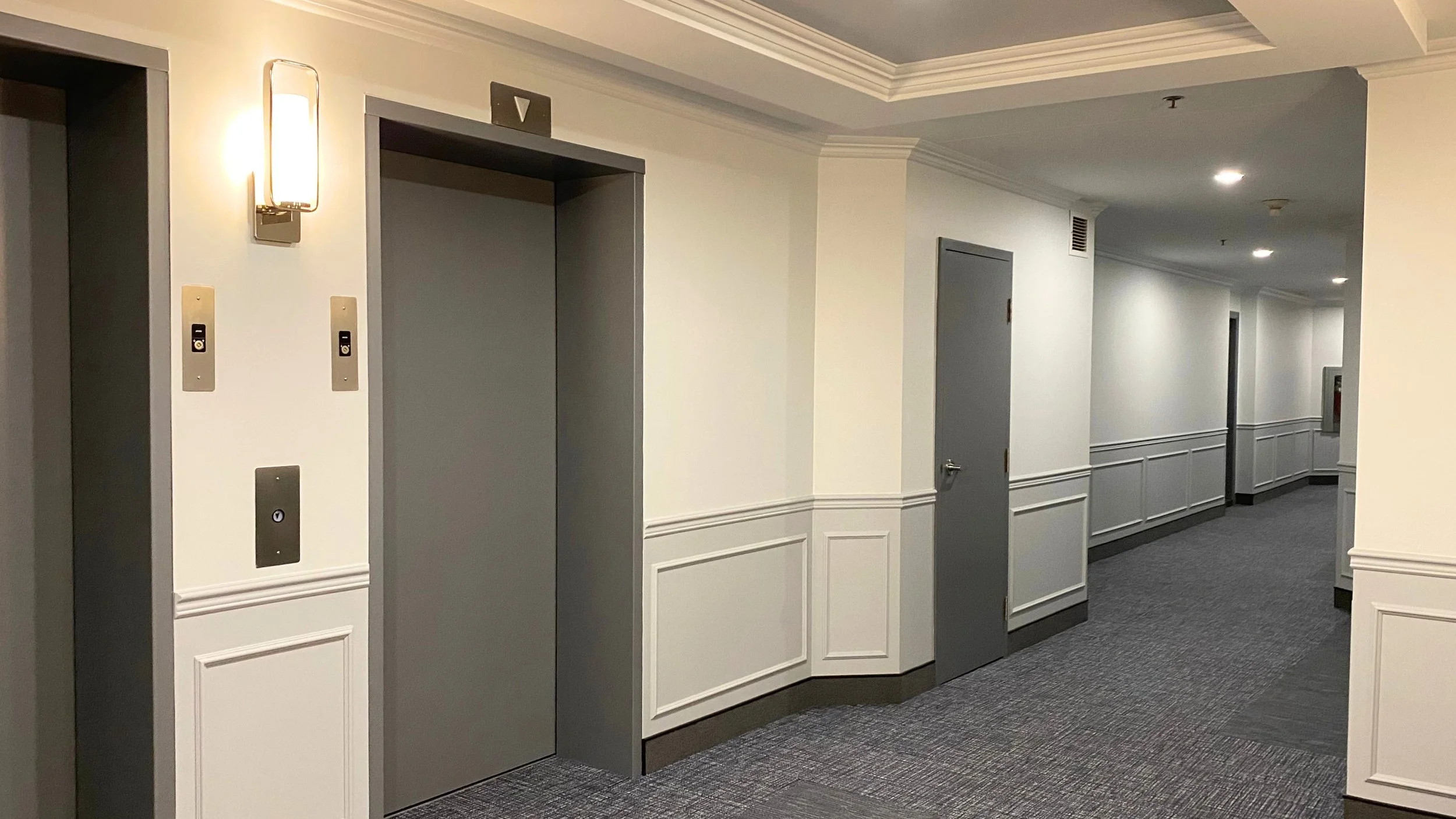 Corridor d'ascenseurs repeint avec lambris deux tons dans un immeuble en copropriété à Laval