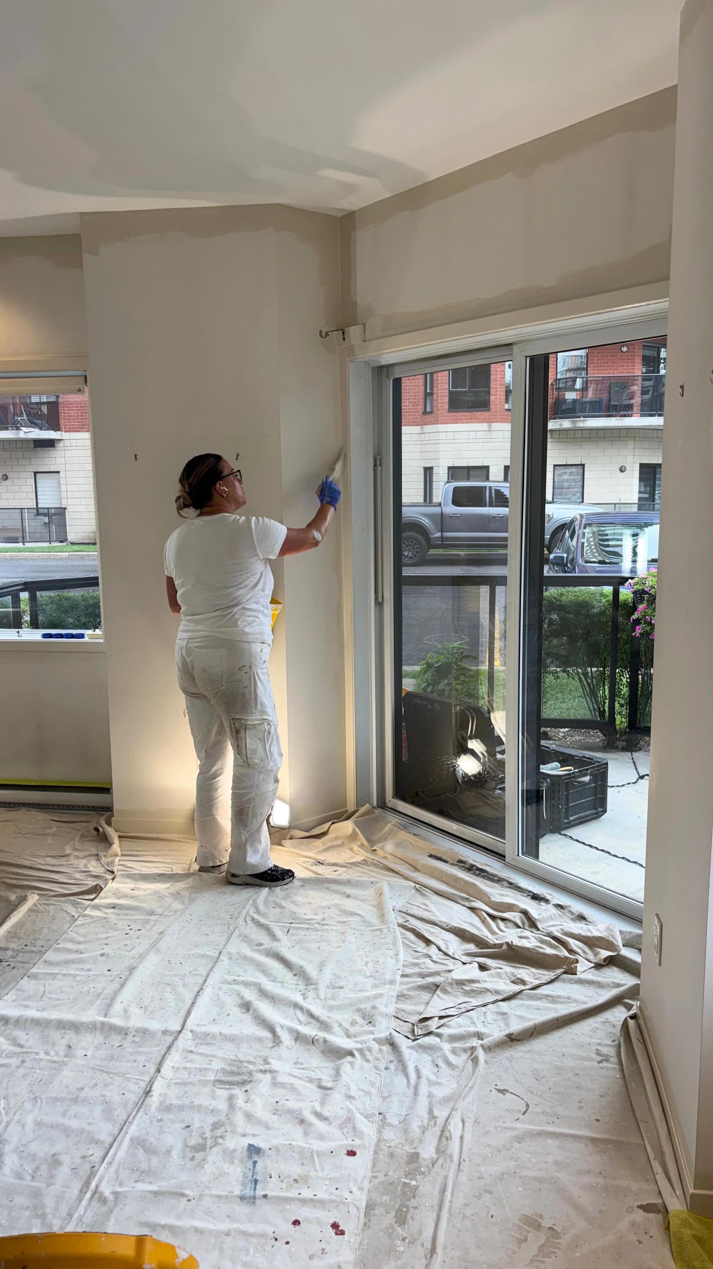 Mélanie Alary, copropriétaire de MP Entretien Peinture, découpant les murs au pinceau près d'une porte-patio dans un condo à Laval