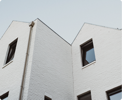 Close-up of the corner of a modern white brick building with windows.