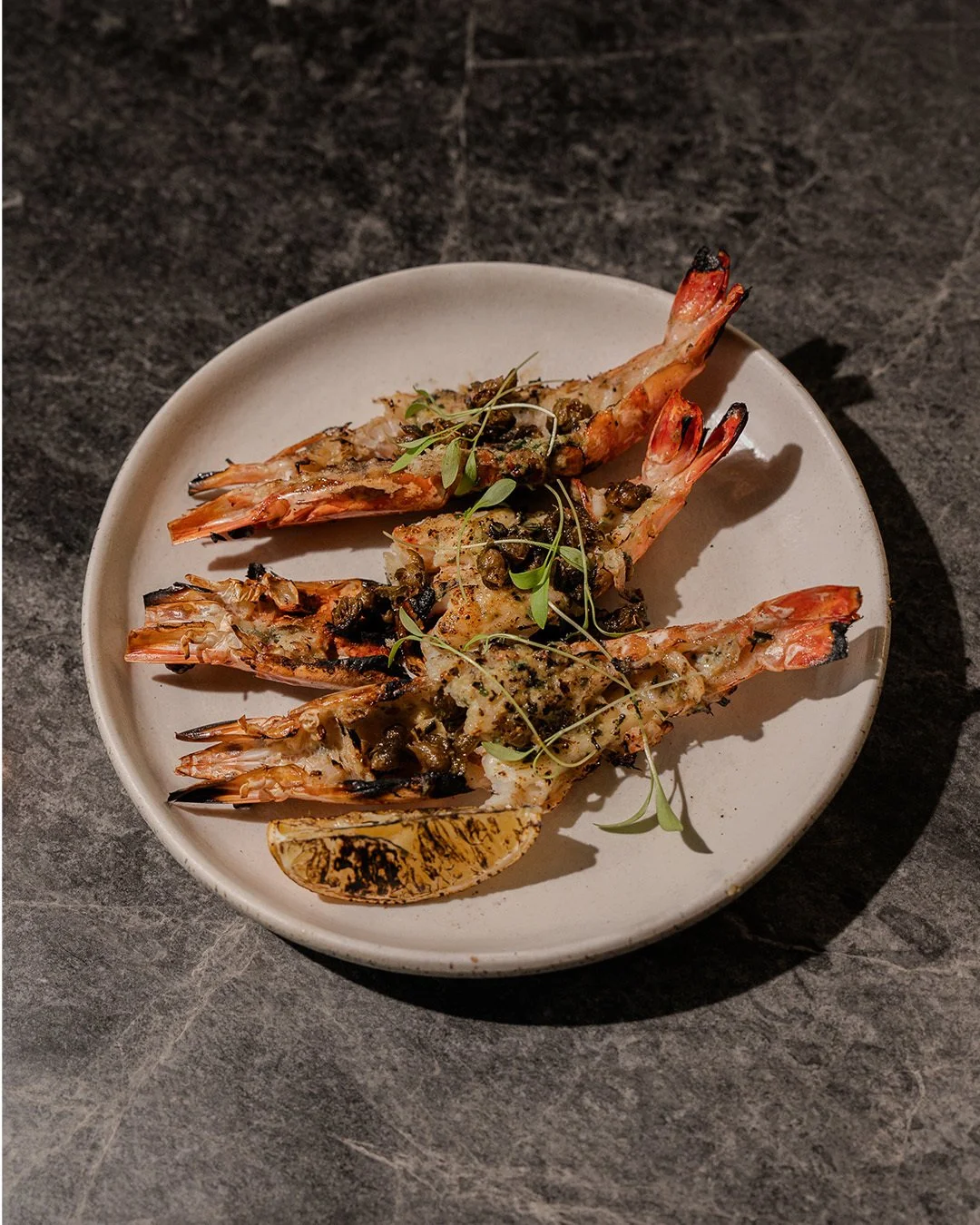 Wood-fired king prawns / Straight from the fire, layered with garlic herb butter and capers