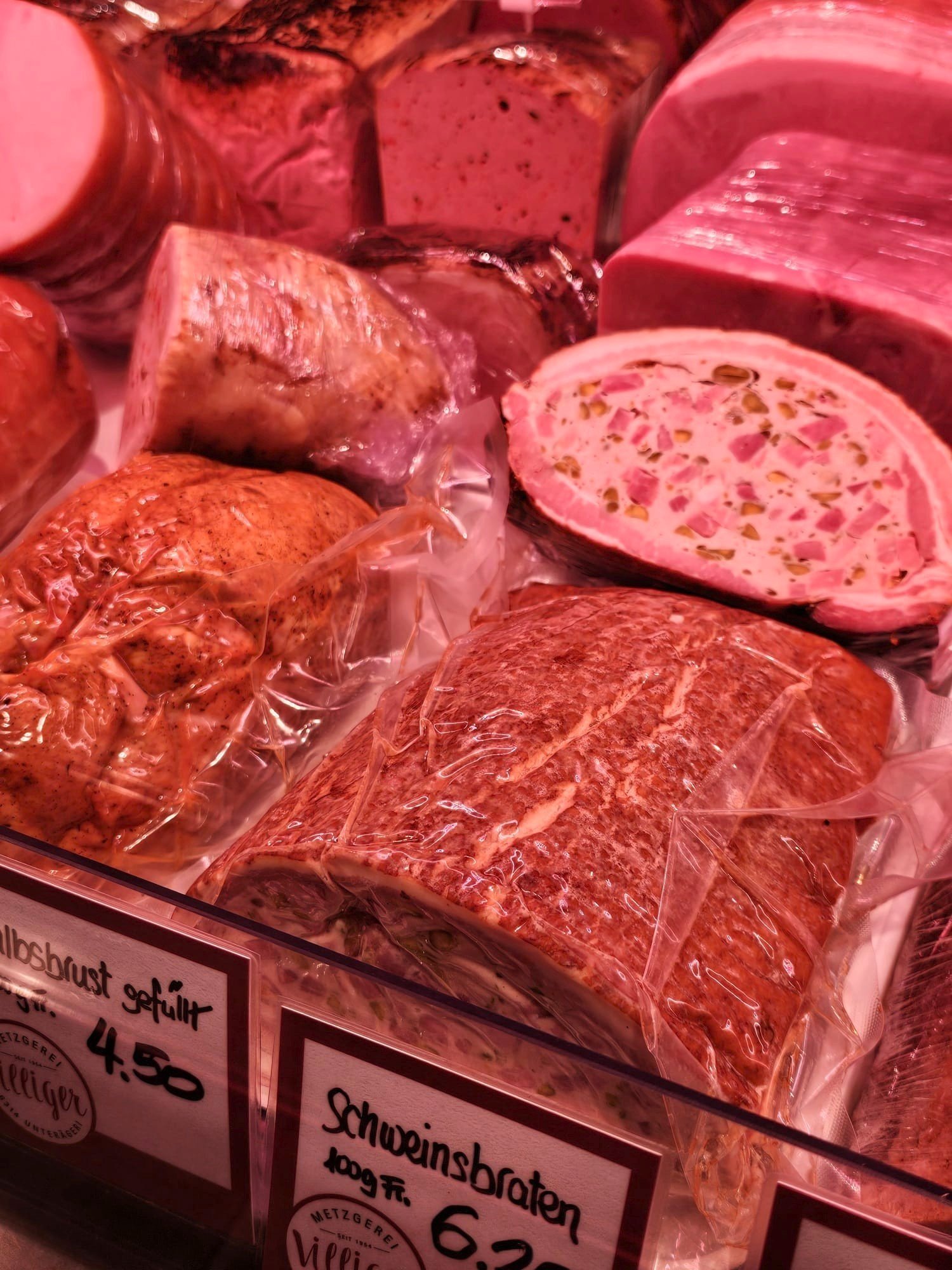 verschiedene sortierte Fleischstücke und Wurstwaren in einem Supermarkt, teilweise in Plastikfolie eingeschweißt, mit Preisschildern
