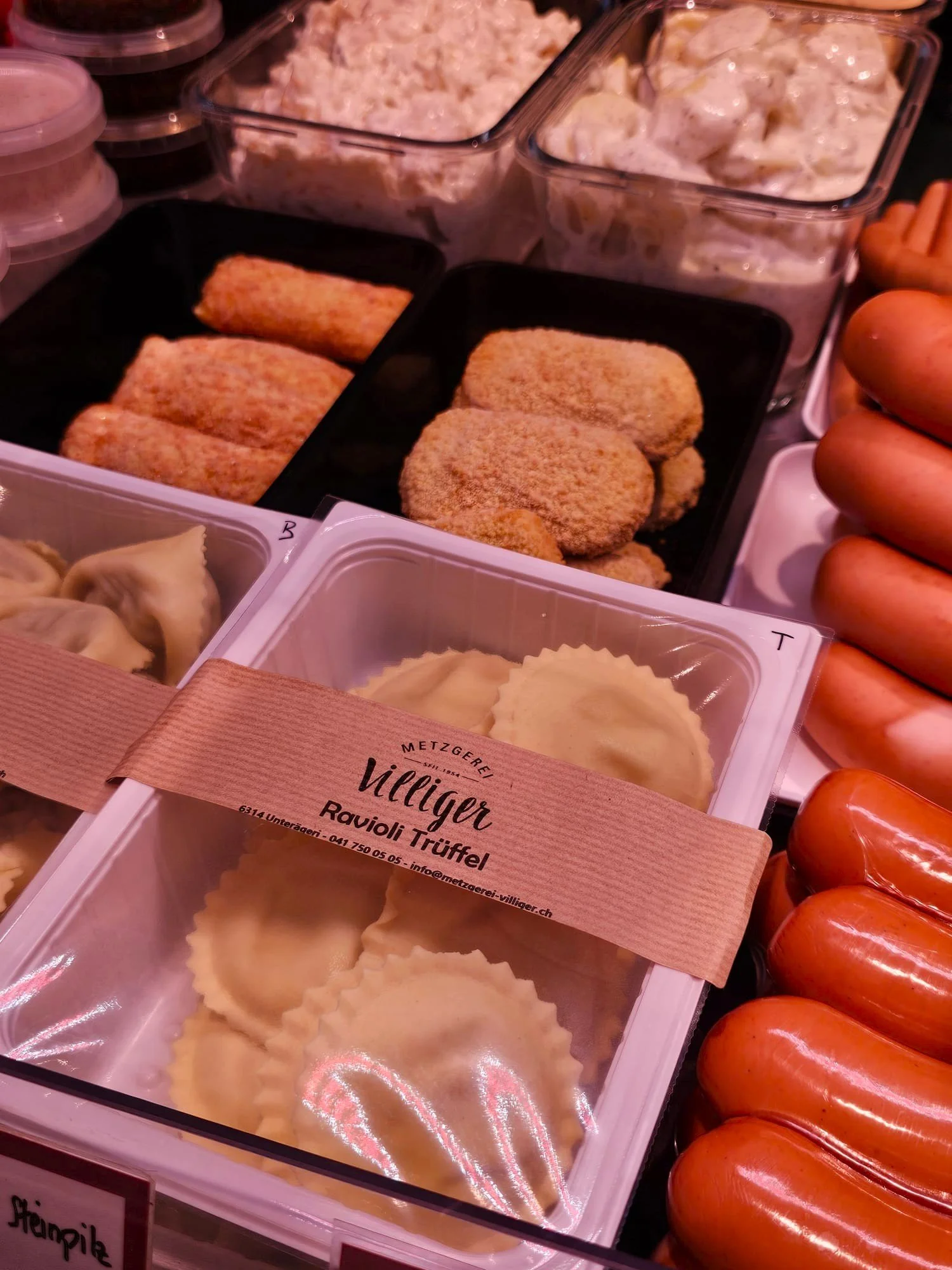 Verschiedene vorverpackte frische Teigwaren, darunter Ravioli mit der Beschriftung 'Ravioli Trüffel', in einem Lebensmittelgeschäft auf einer Verkaufsfläche.