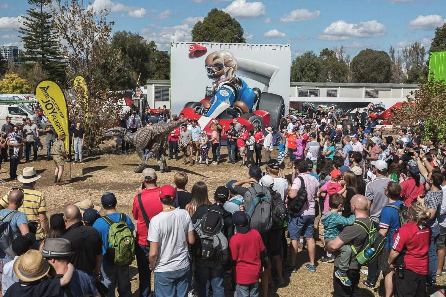 a large crowd gathers round a street art mural in a shipping container and the Melbourne Grand Prix