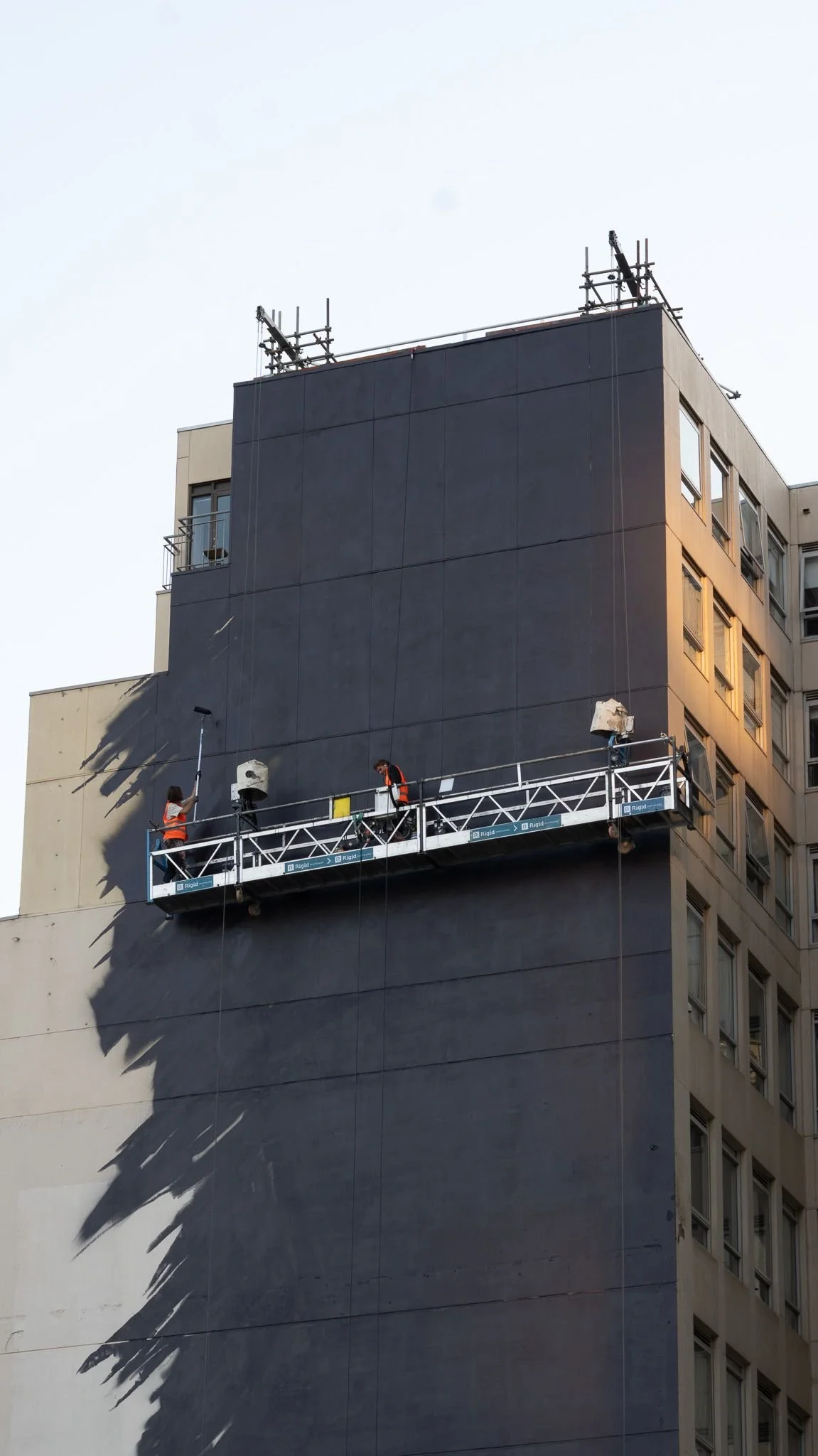 Swing stage on the blank 13-storey wall of Clement House