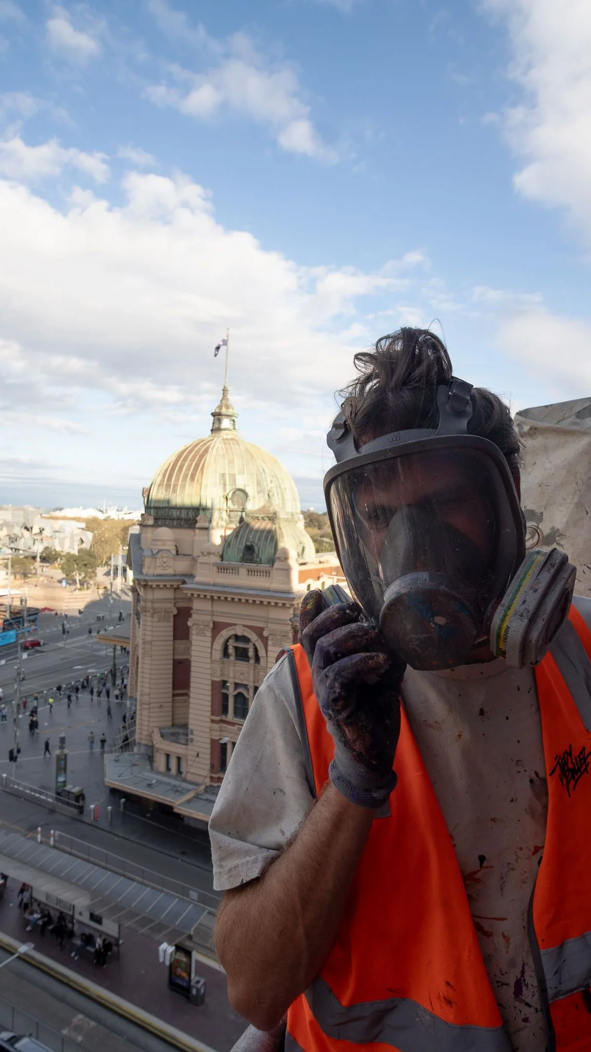 Painter in a respirator with the Flinders Street Station dome behind
