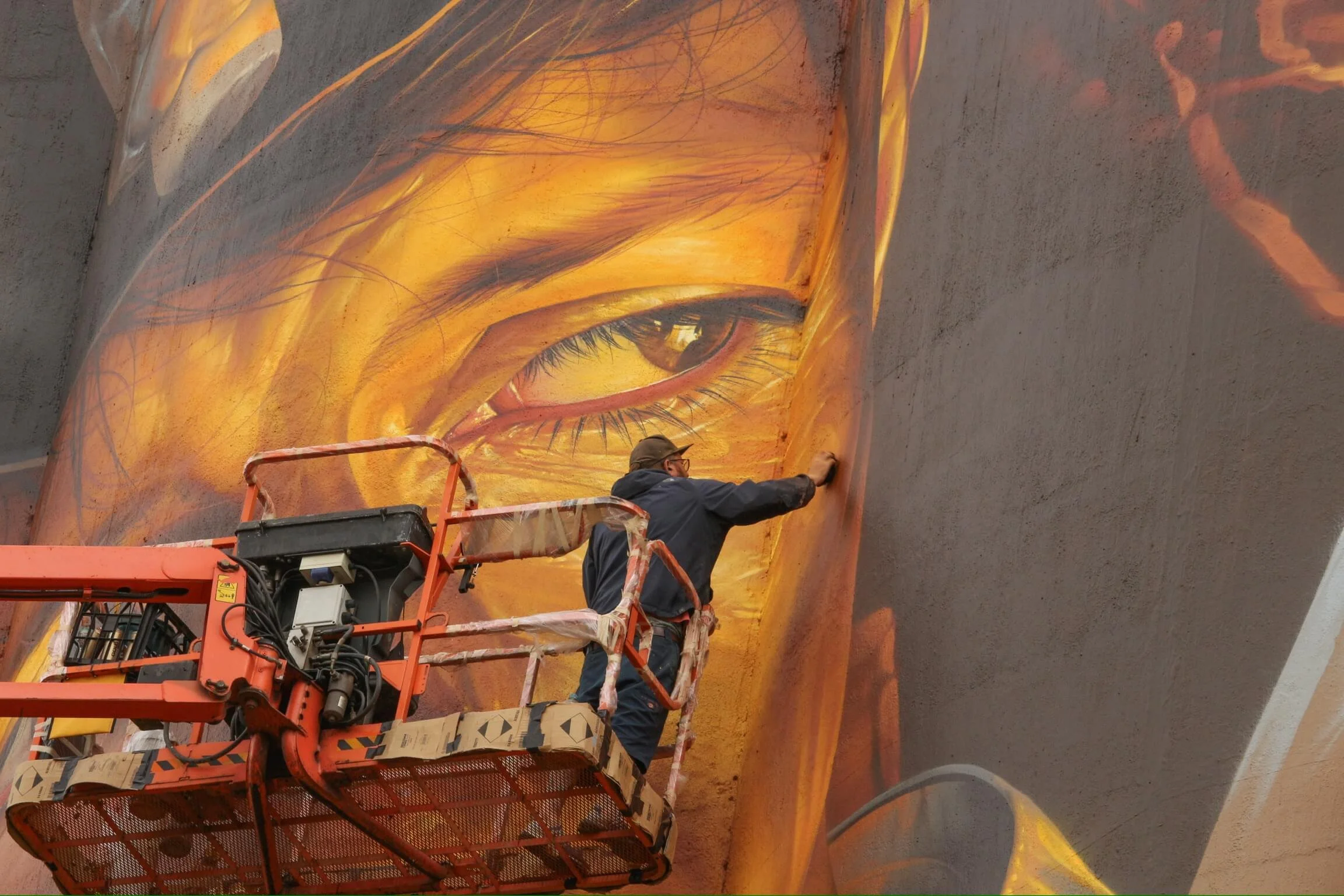 a image of artist smug one painting a giant portrait on a grain silo