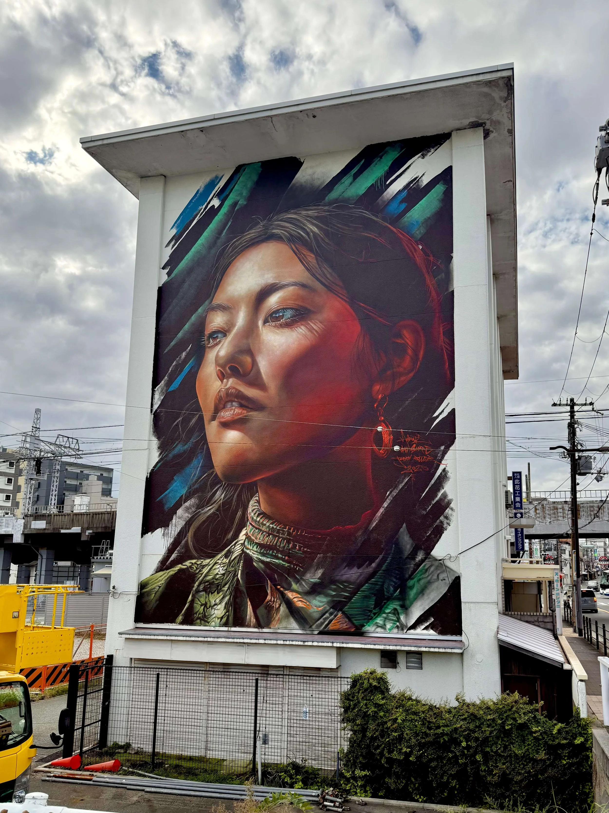mural of a japanse girl on a large facade looking towards the sky with hope 