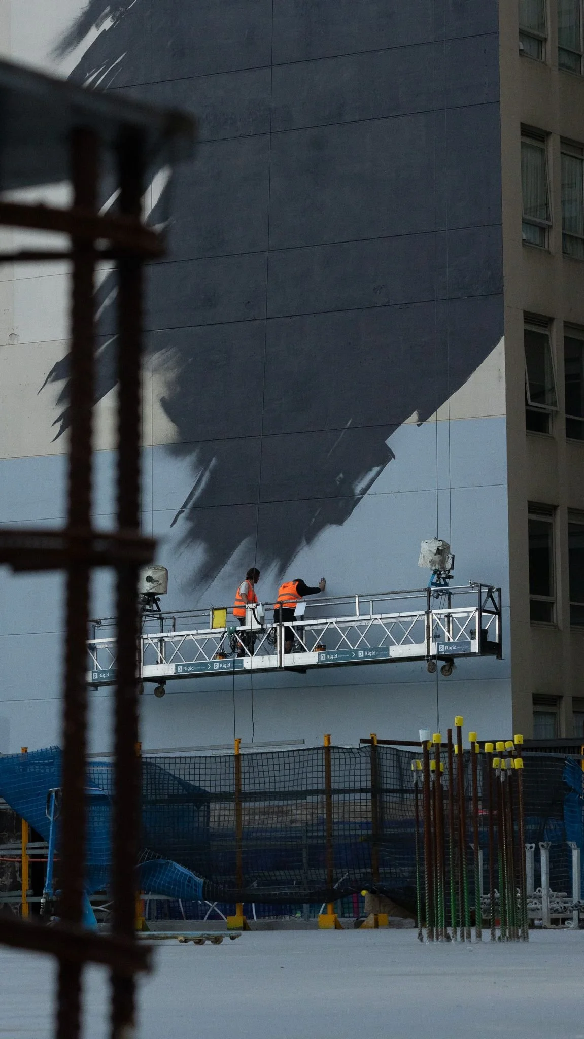 The swing stage seen through rebar on the neighbouring Lendlease site