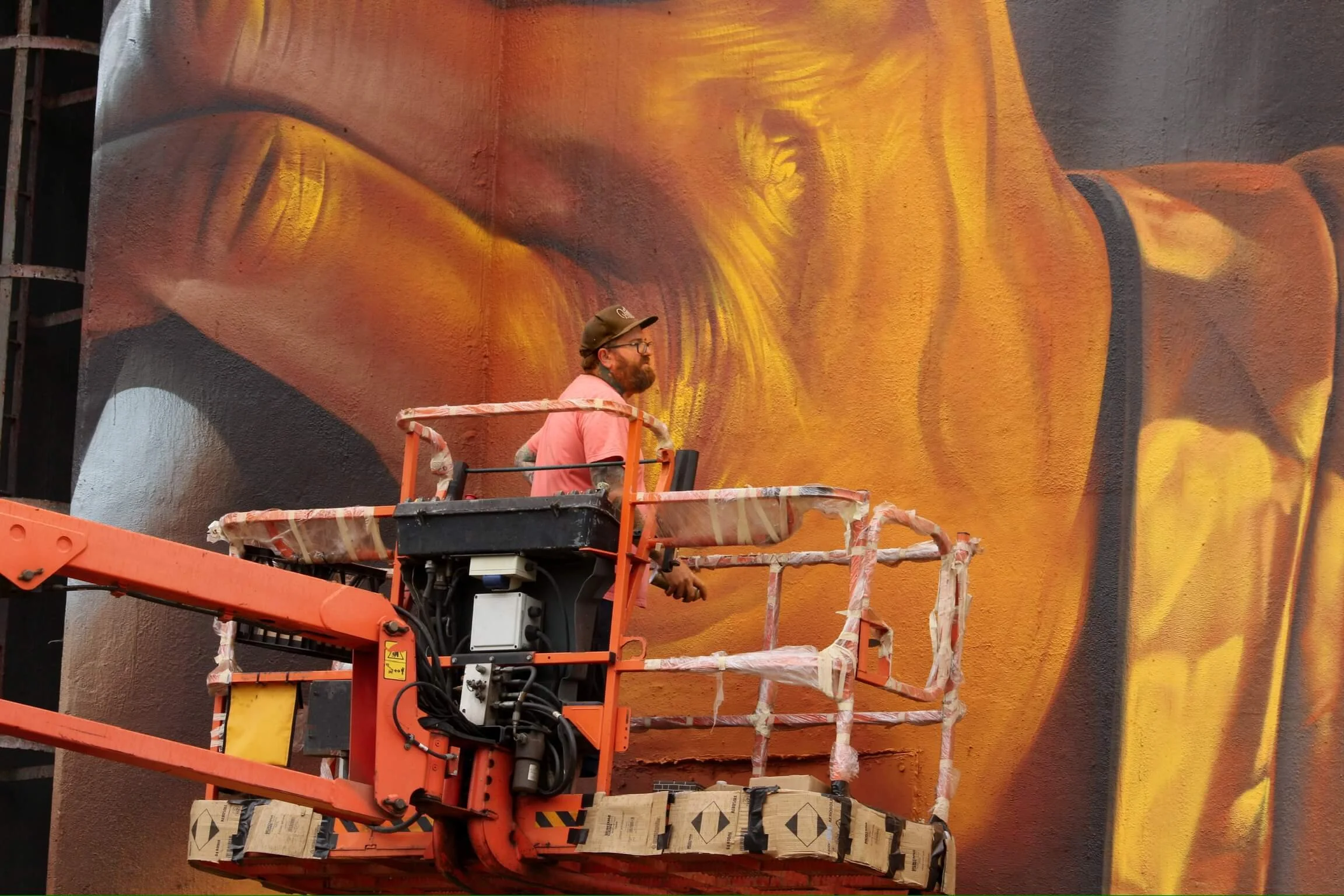 close up image of artist smug painting a silo art work in deep oranges like the colour of a mine