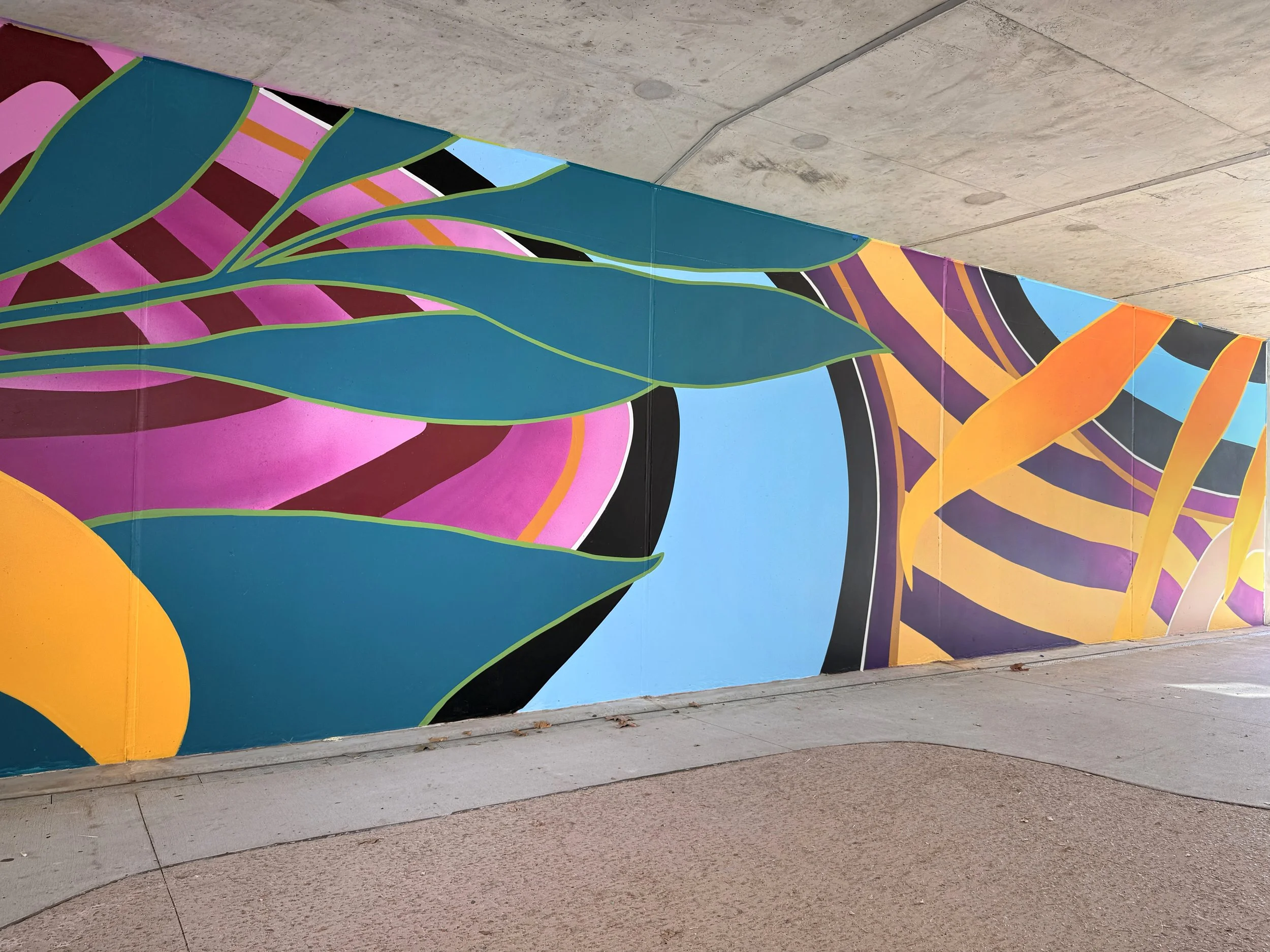 Colorful street mural featuring abstract shapes and bold lines, painted on a concrete wall.