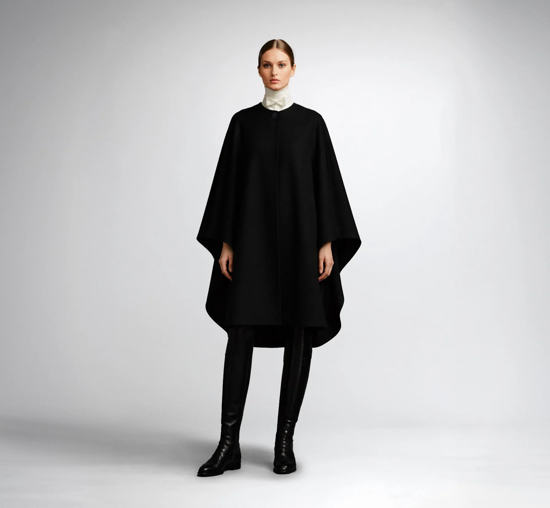 Front view of the CASTELLAINES black icon cape with  flowy silhouette and signature button closure