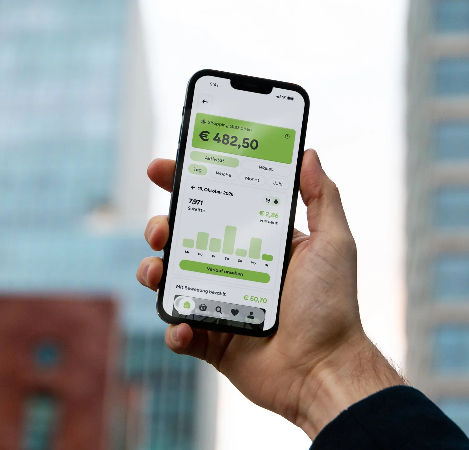 Nahaufnahme einer Hand, die ein Smartphone hält. Auf dem Bildschirm ist die move2pay App mit Kontoinformationen in grün und weiß zu sehen, inklusive Guthaben, Aktivitäten und Diagrammen, in einer hellen Umgebung.