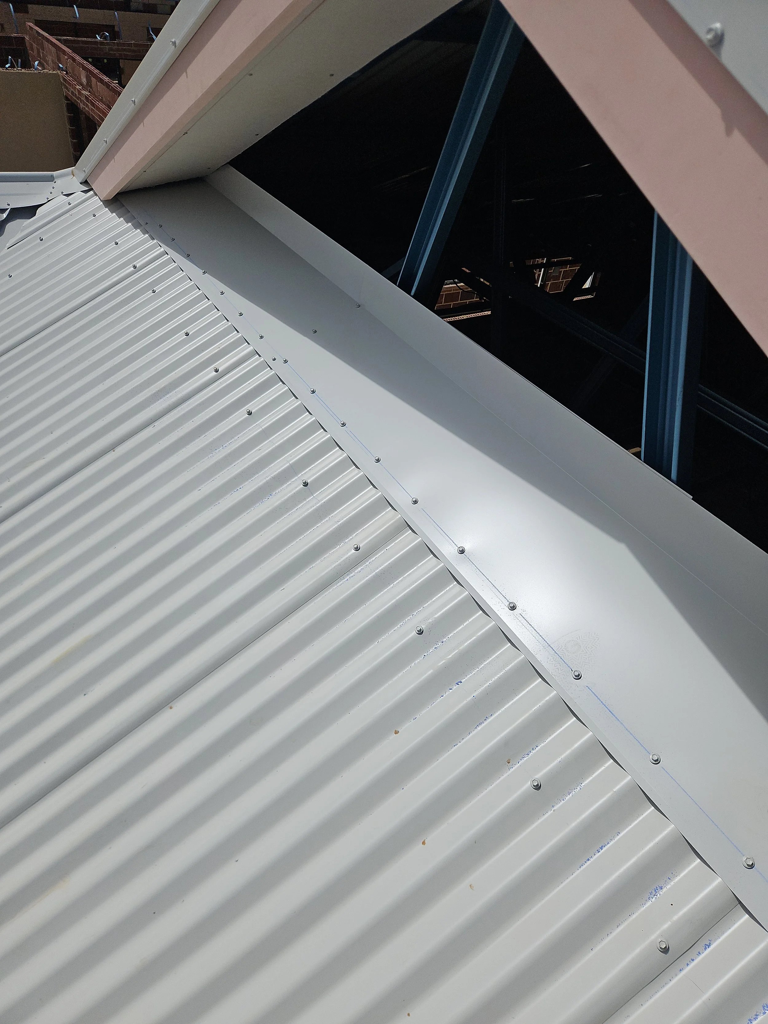 Close-up of a metal roof with corrugated panels and a white metal flashing along the edge.