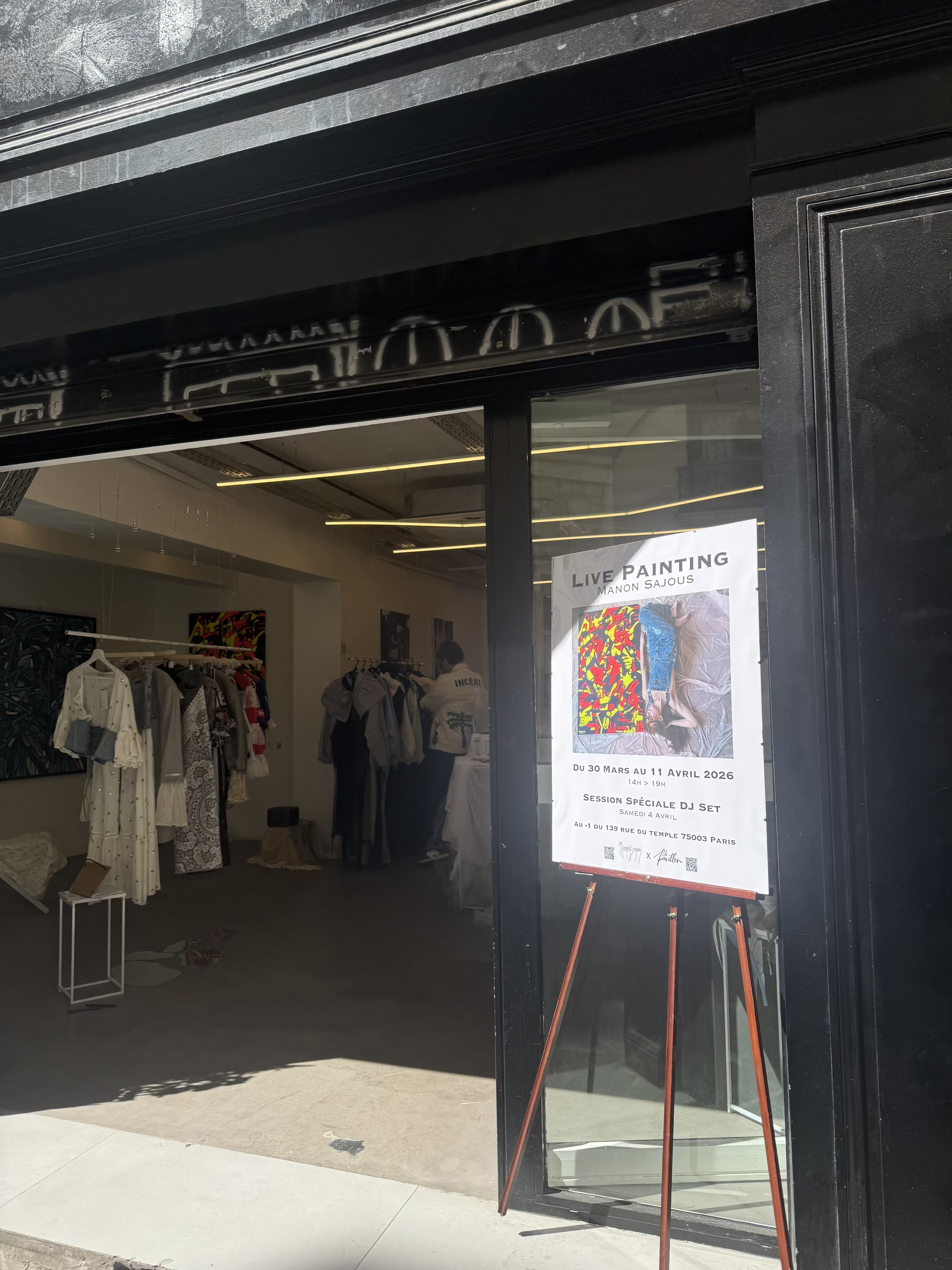 Panneau à l'entrée d'une galerie d'art annonçant une exposition de peinture en direct de Manon Sajous du 30 mars au 11 avril 2026, avec une session DJ le samedi 4 avril, situé au 139 rue du Temple, Paris.