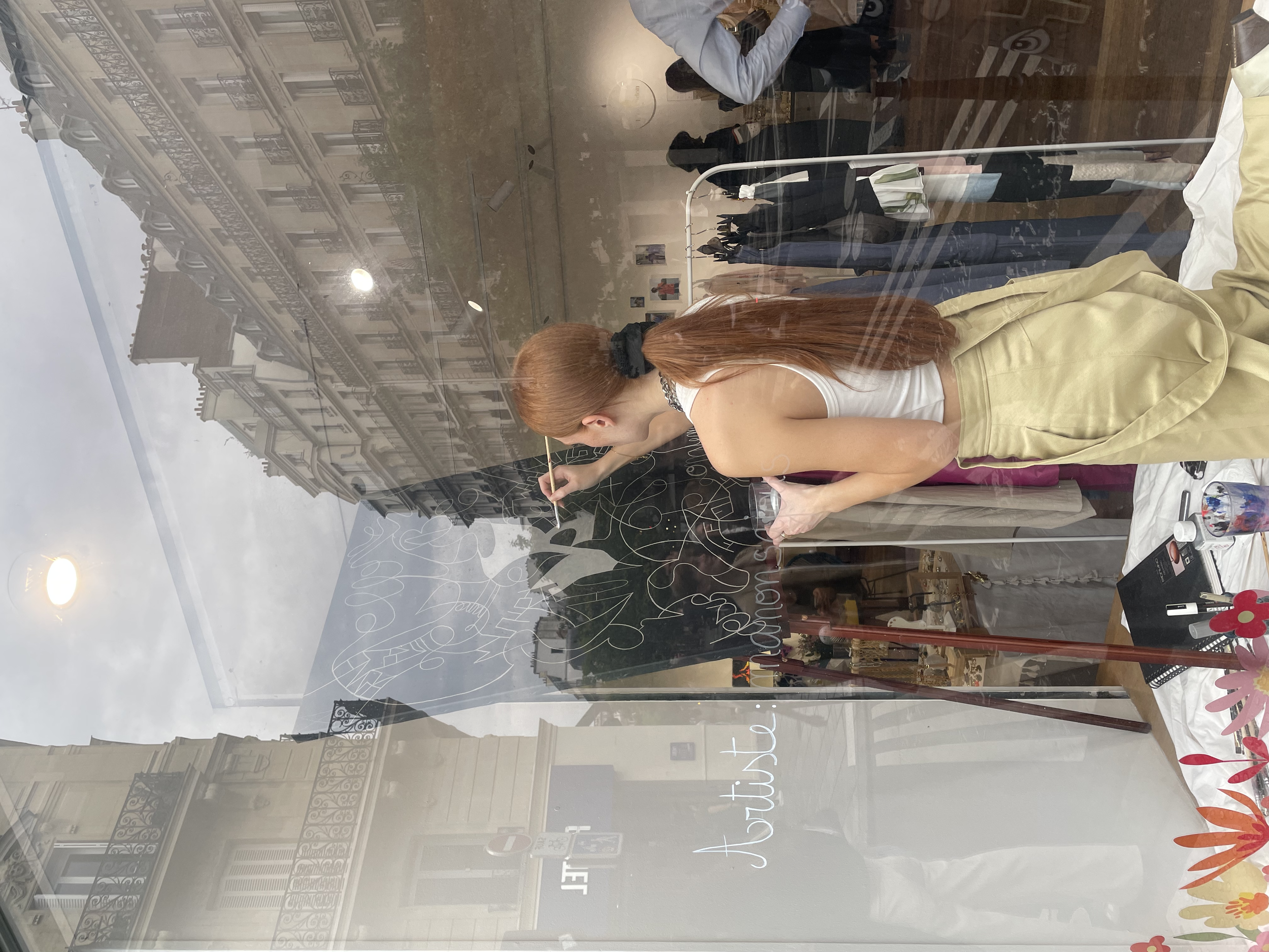 L'artiste peintre, Manon SAJOUS, qui peins dans la vitrine d'un pop up à Paris. Elle peint dans la vitrine.