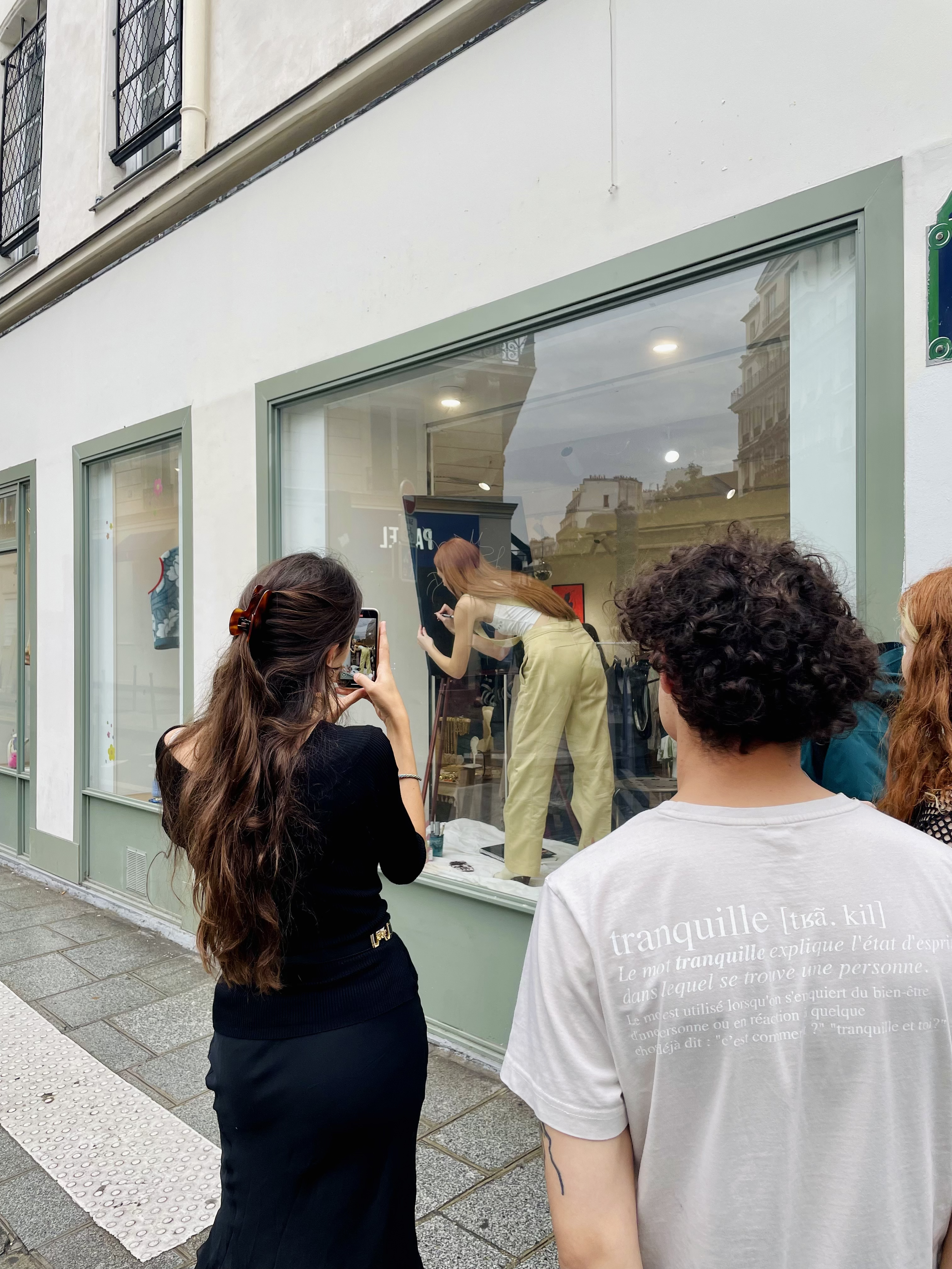 Groupe de personnes regardant une vitrine d'art où l'artiste Manon SAJOUS peint.