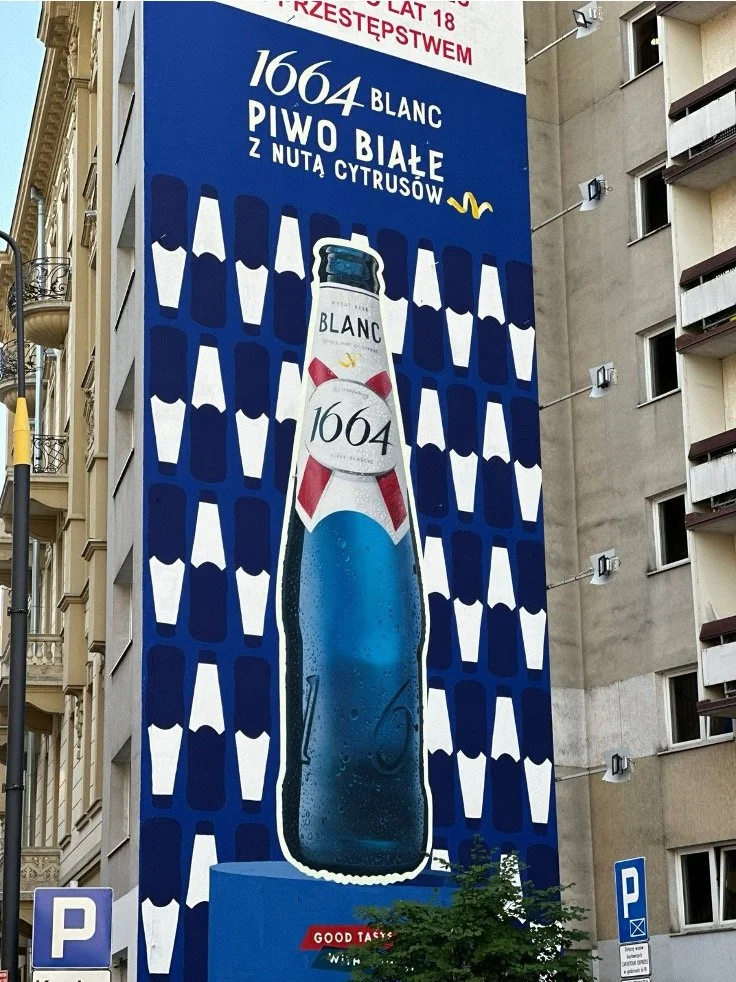 Artystyczny mural reklamowy Urban Ads – piwo 1664 Blanc z nutą cytrusów na elewacji kamienicy