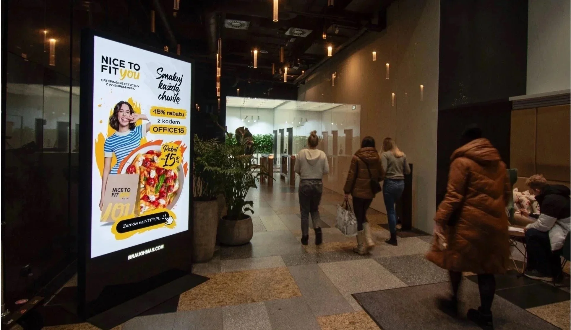 Reklama 'Nice To Fit You' na digitalowym citylighcie Urban Ads w pasażu handlowym – kampania z rabatem -15%