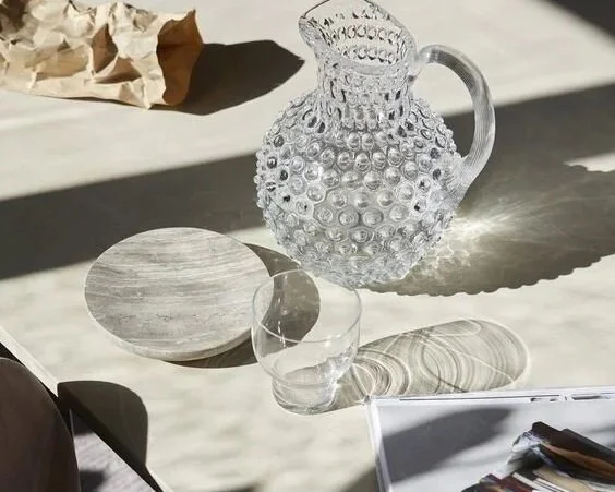 Simple glass carafe on a minimalist wooden table — symbolizing clarity, focus, and distinctive positioning in a world full of expertise