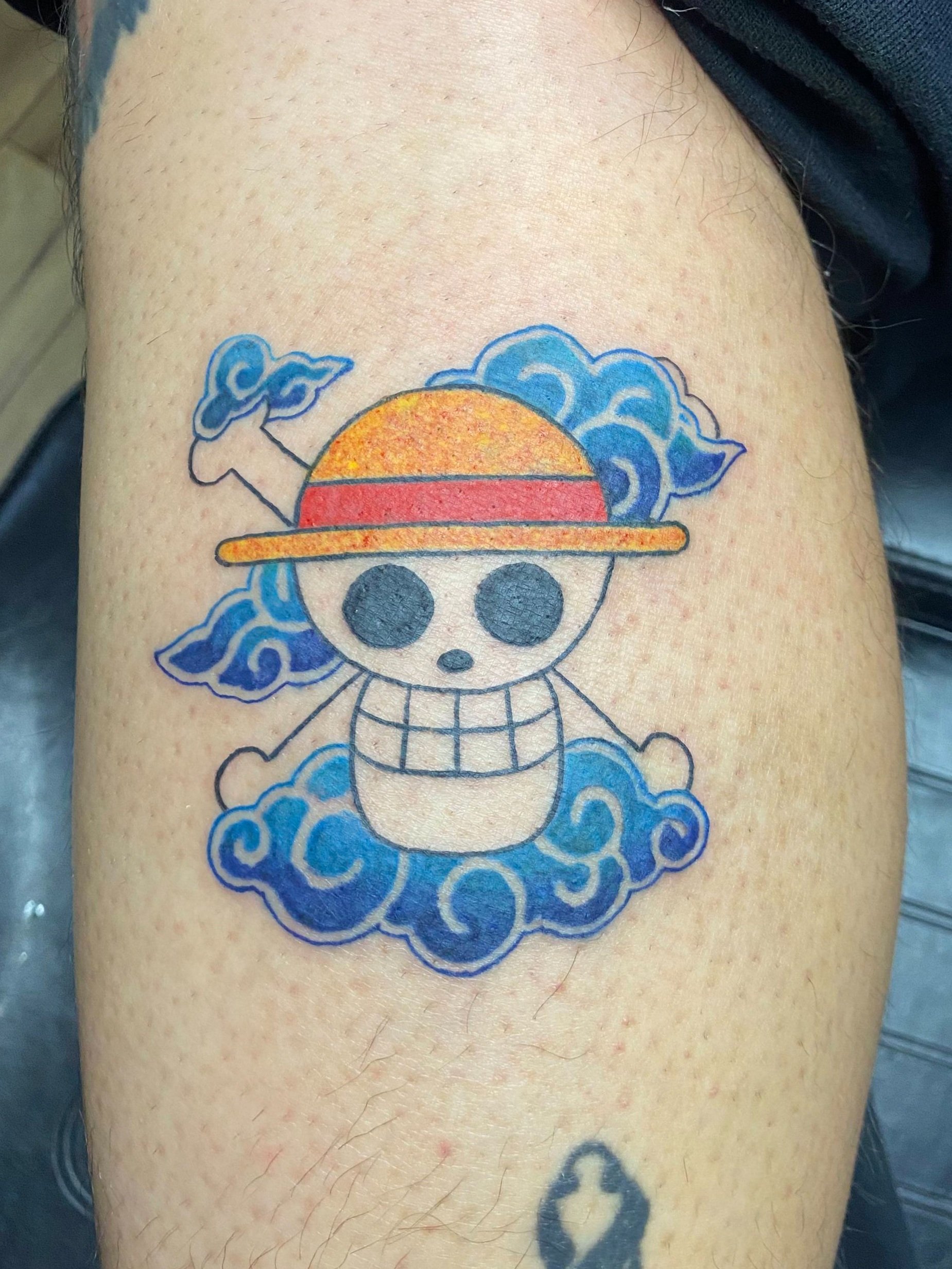 One Piece anime tattoo with stylized clouds in full color