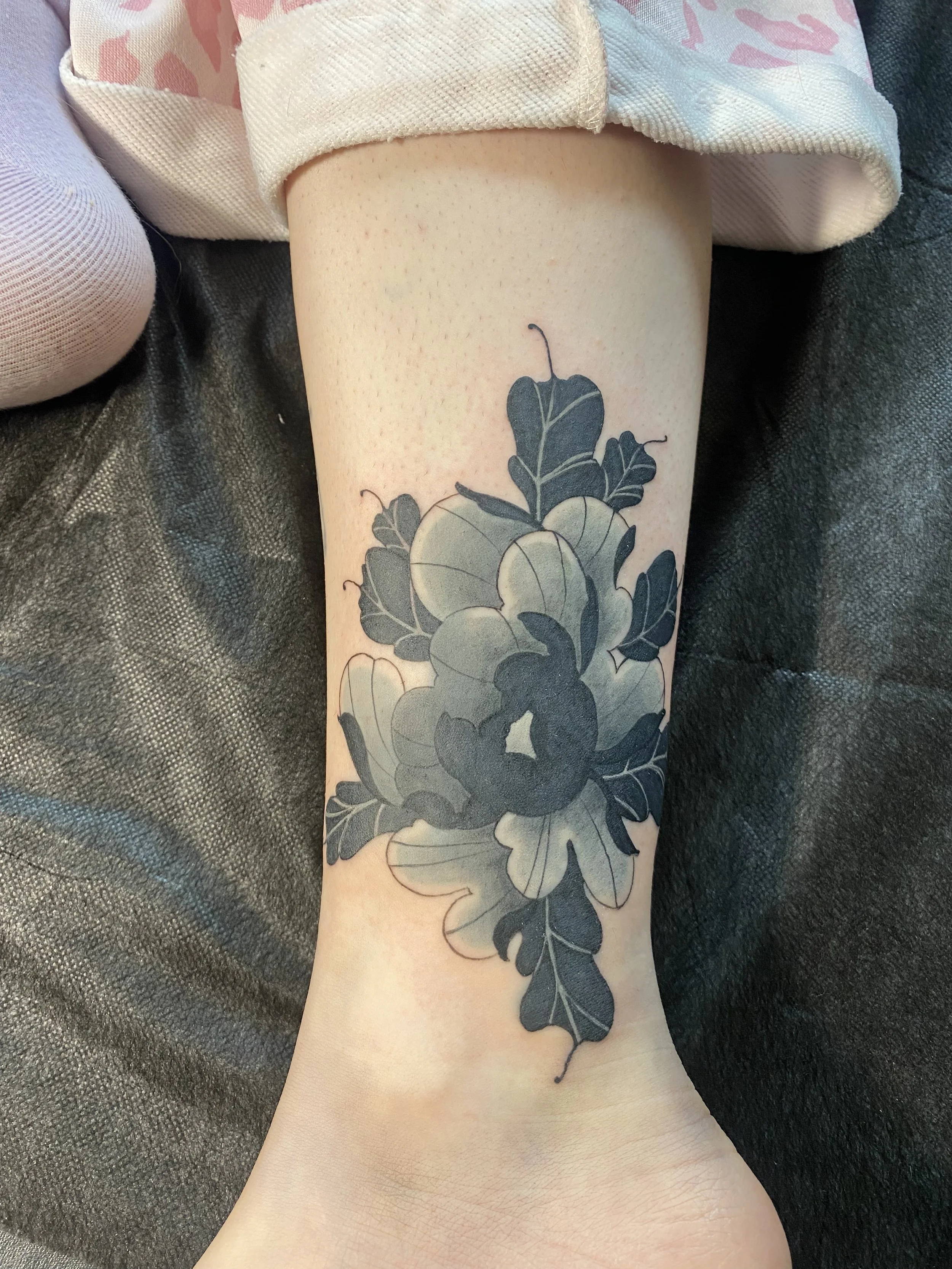 American Traditional-inspired black and grey peony tattoo by Denver tattoo artist Joshua Socrates in RiNo.