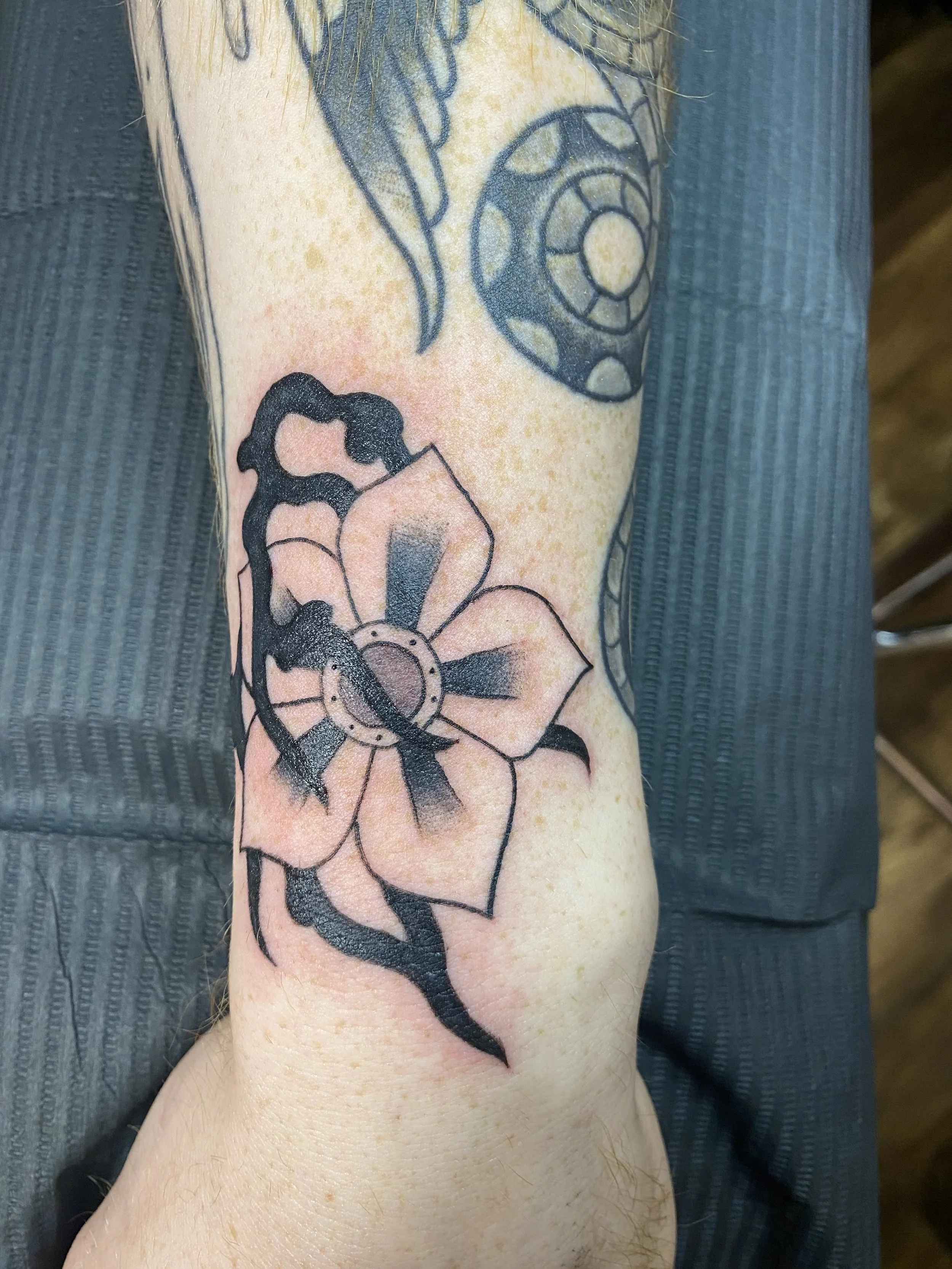 American Traditional flower tattoo with flames by Denver tattoo artist Joshua Socrates in RiNo.