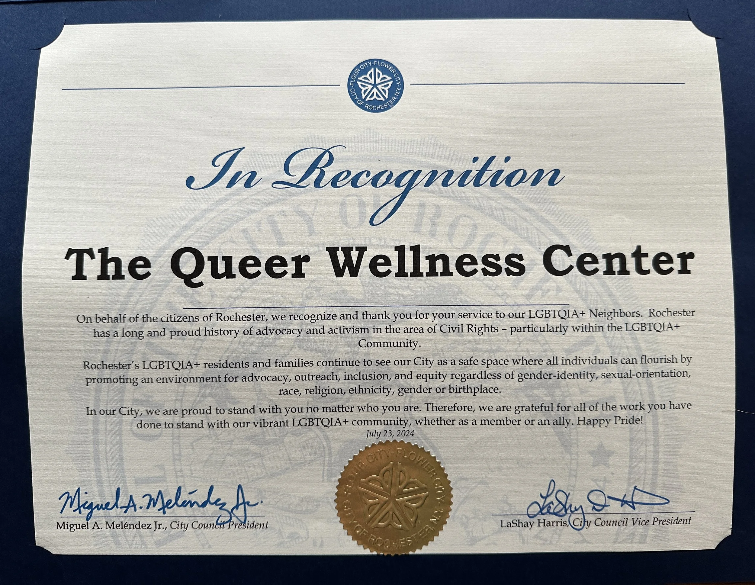 Certificate of recognition awarded to The Queer Wellness Center by the City of Rochester, dated July 23, 2024, with signatures of Miguel A. Melendez Jr. and LaShay Harris, featuring a gold seal at the bottom.