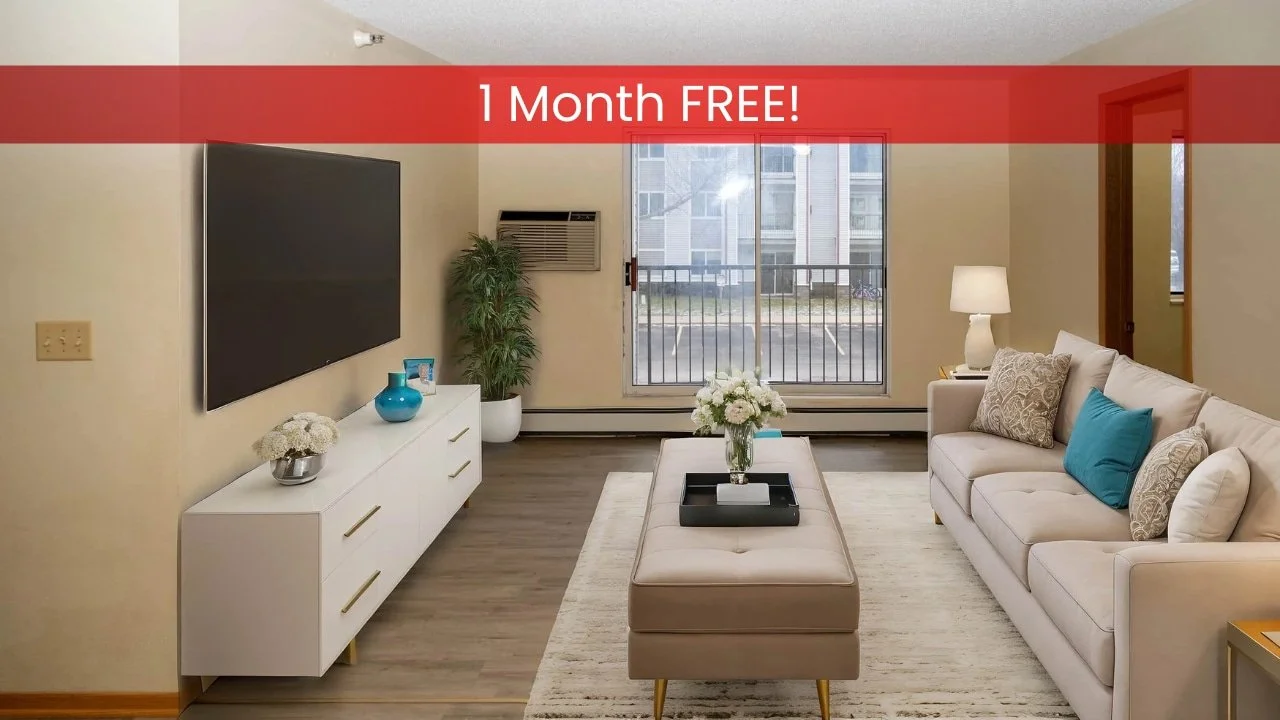 Modern living room in apartments in Rochester with a beige sofa, wall-mounted TV, plants, and a large window for natural light.