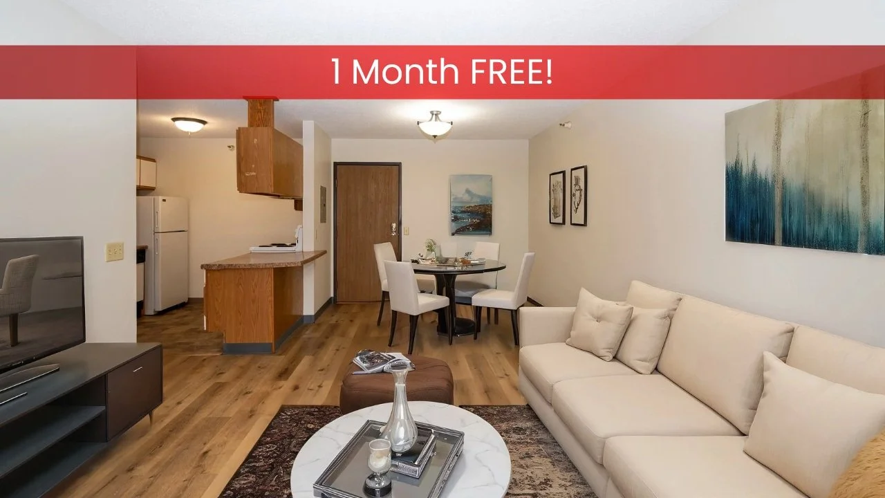 A modern apartments in Rochester living room with a beige sofa, round coffee table, dining area, and open kitchen with wood accents.