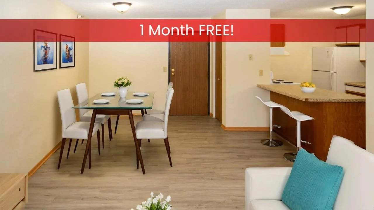 Modern apartments in Rochester feature a dining and kitchen area with a glass table, white chairs, barstools, and neutral colors.