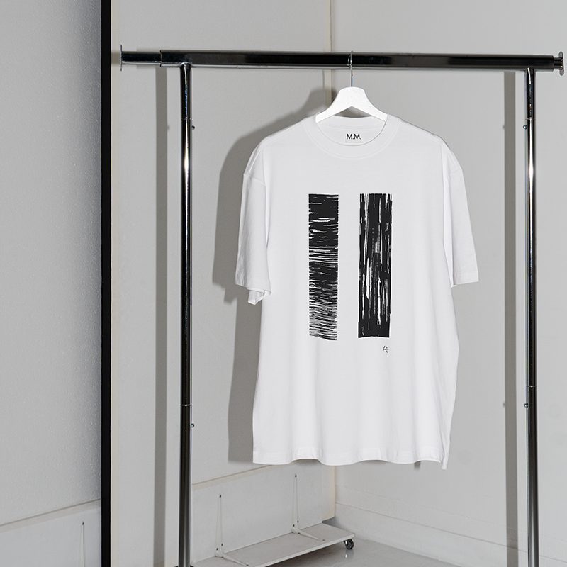 T-shirt blanc avec des motifs noirs suspendu à un portant