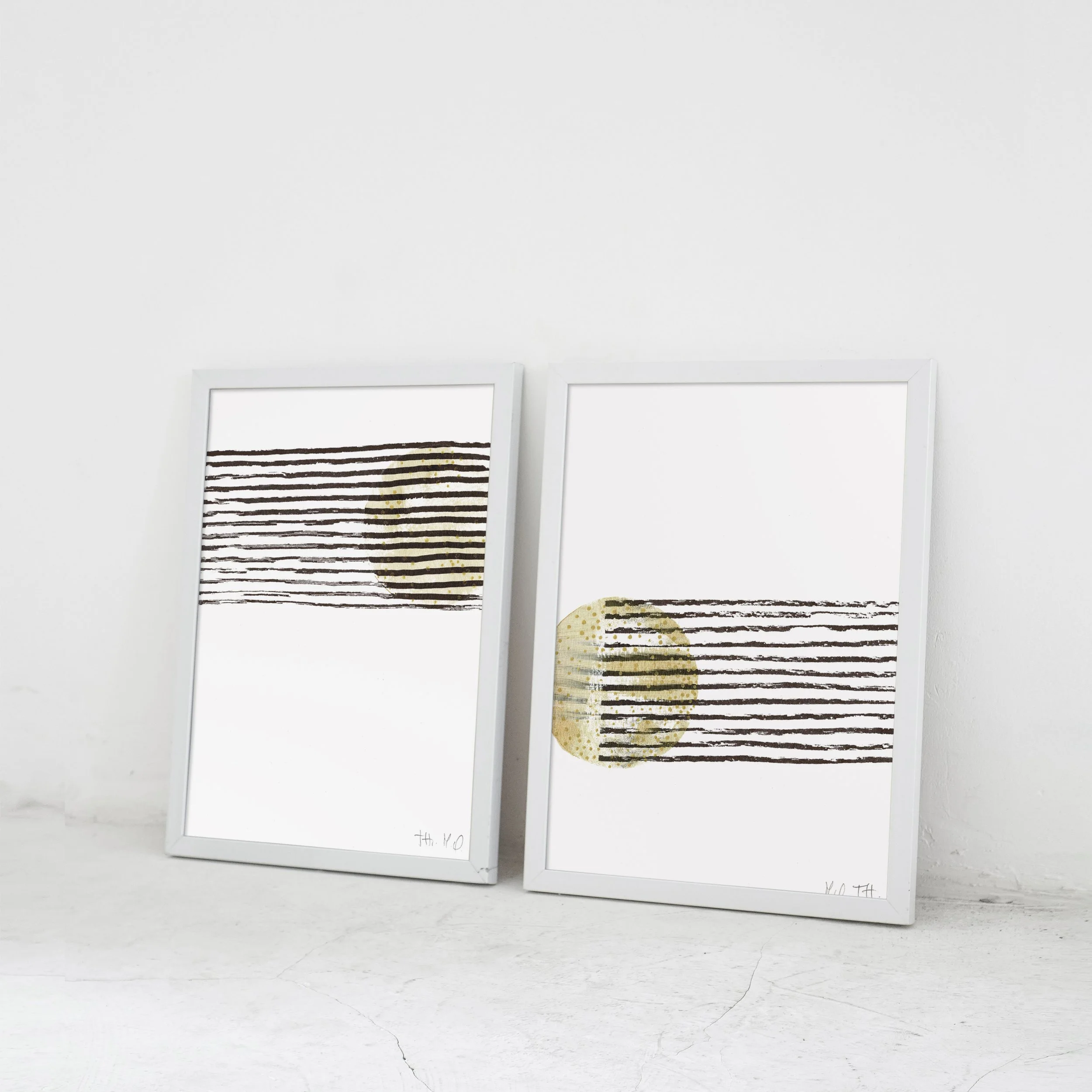 Deux tableaux minimalistes avec des lignes noires horizontales et un cercle doré sur un fond blanc.