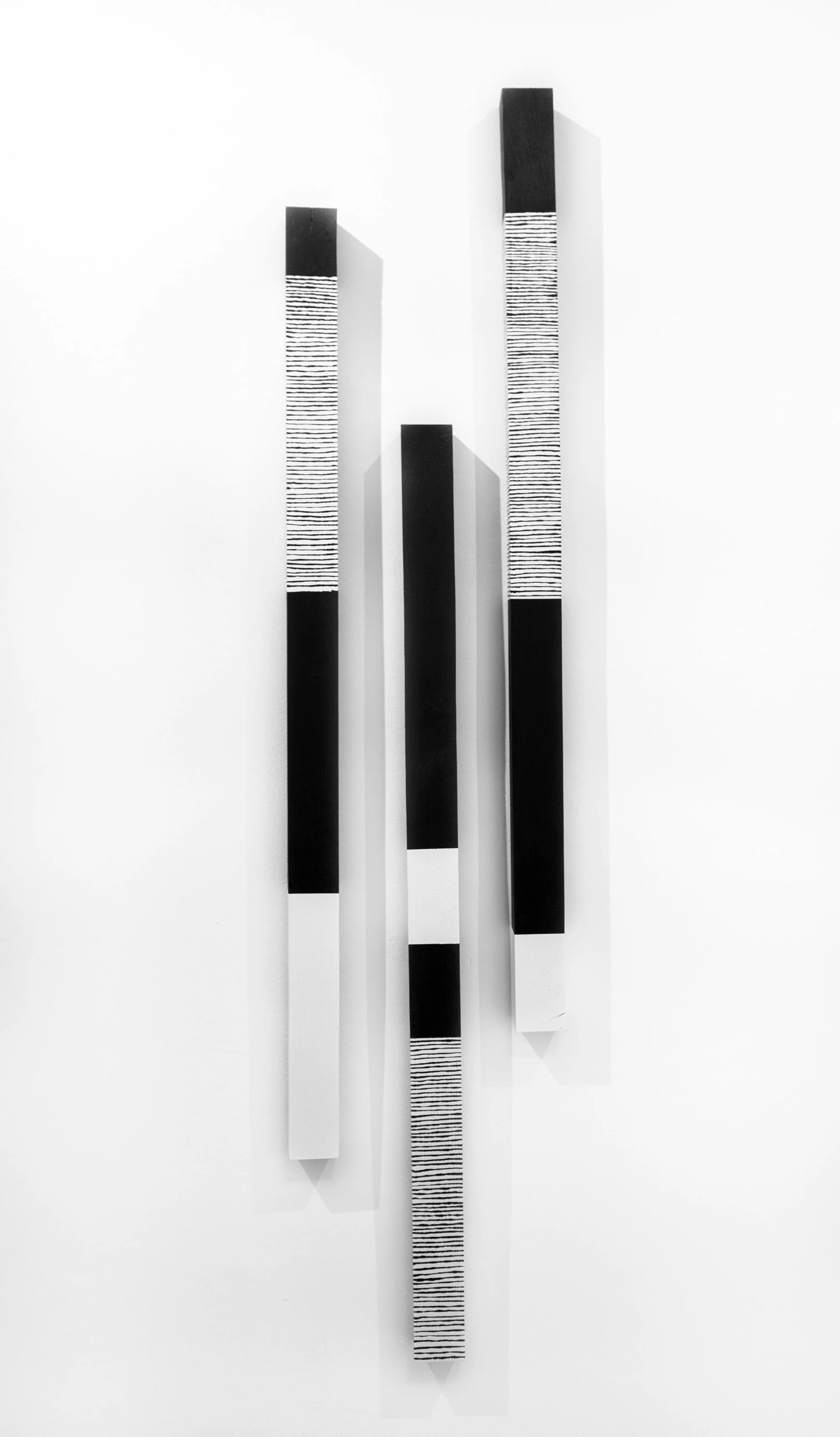 Abstract black and white striped wall art with several vertical rectangular panels of varying heights and widths, some with horizontal lines.