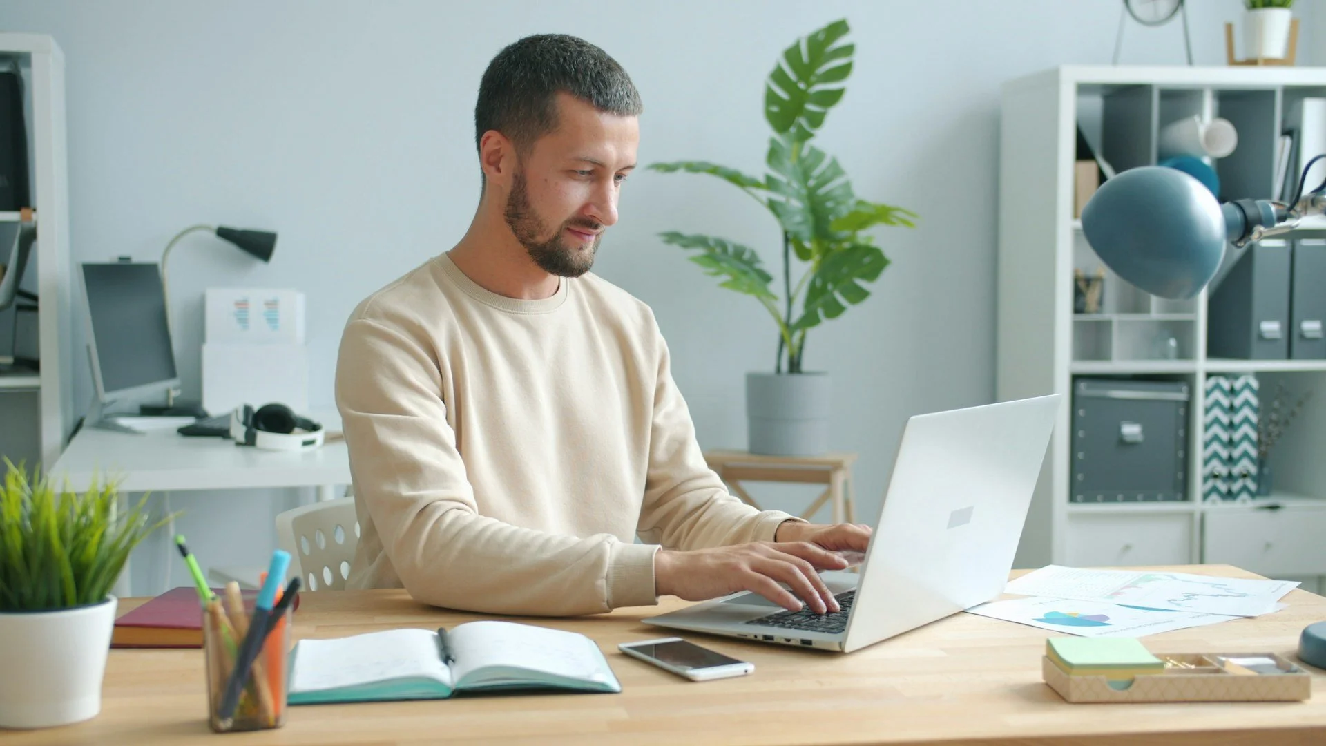 man typing on laptop at desk in an office space
