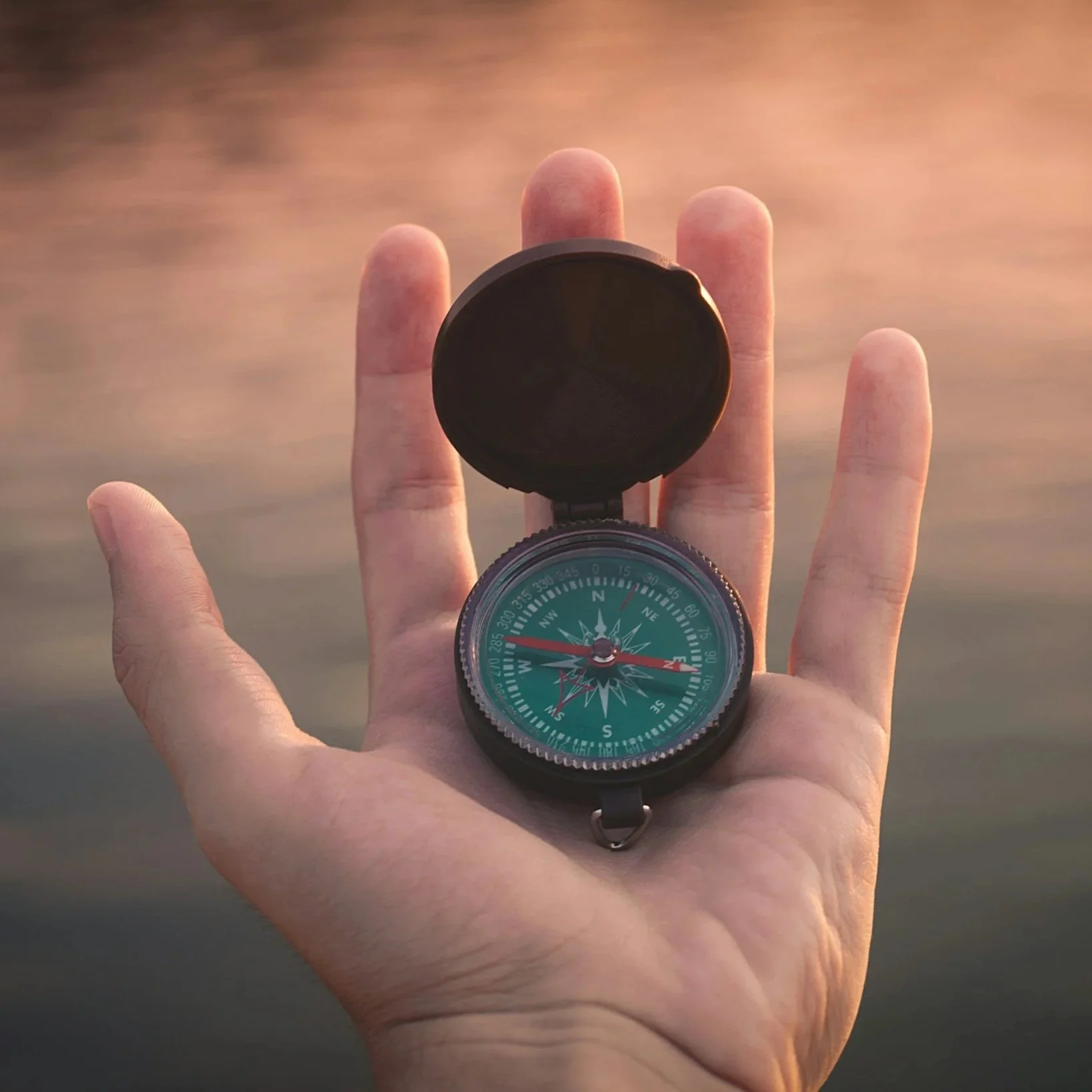 a green compass held in the palm of a hand