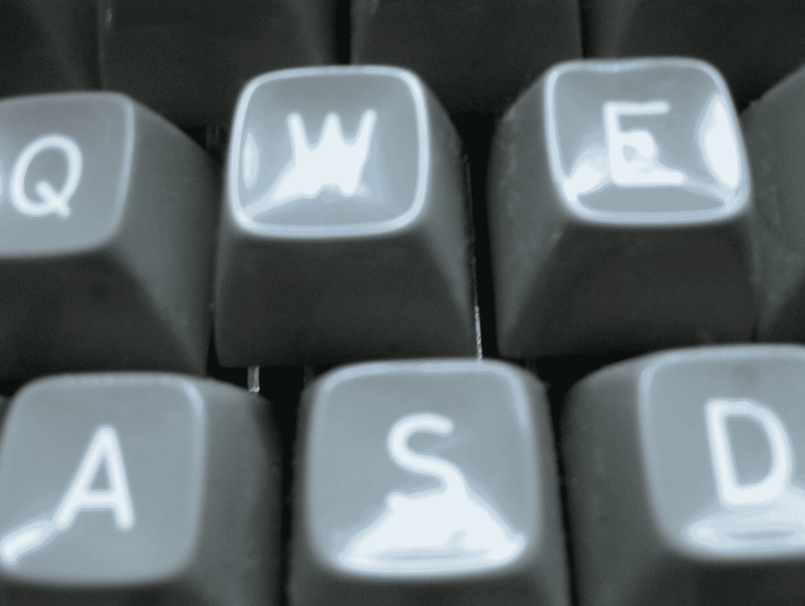 Macro close-up of typewriter keys showing the letters Q, W, E, A, S, D, softly lit, representing writing and the creative process..