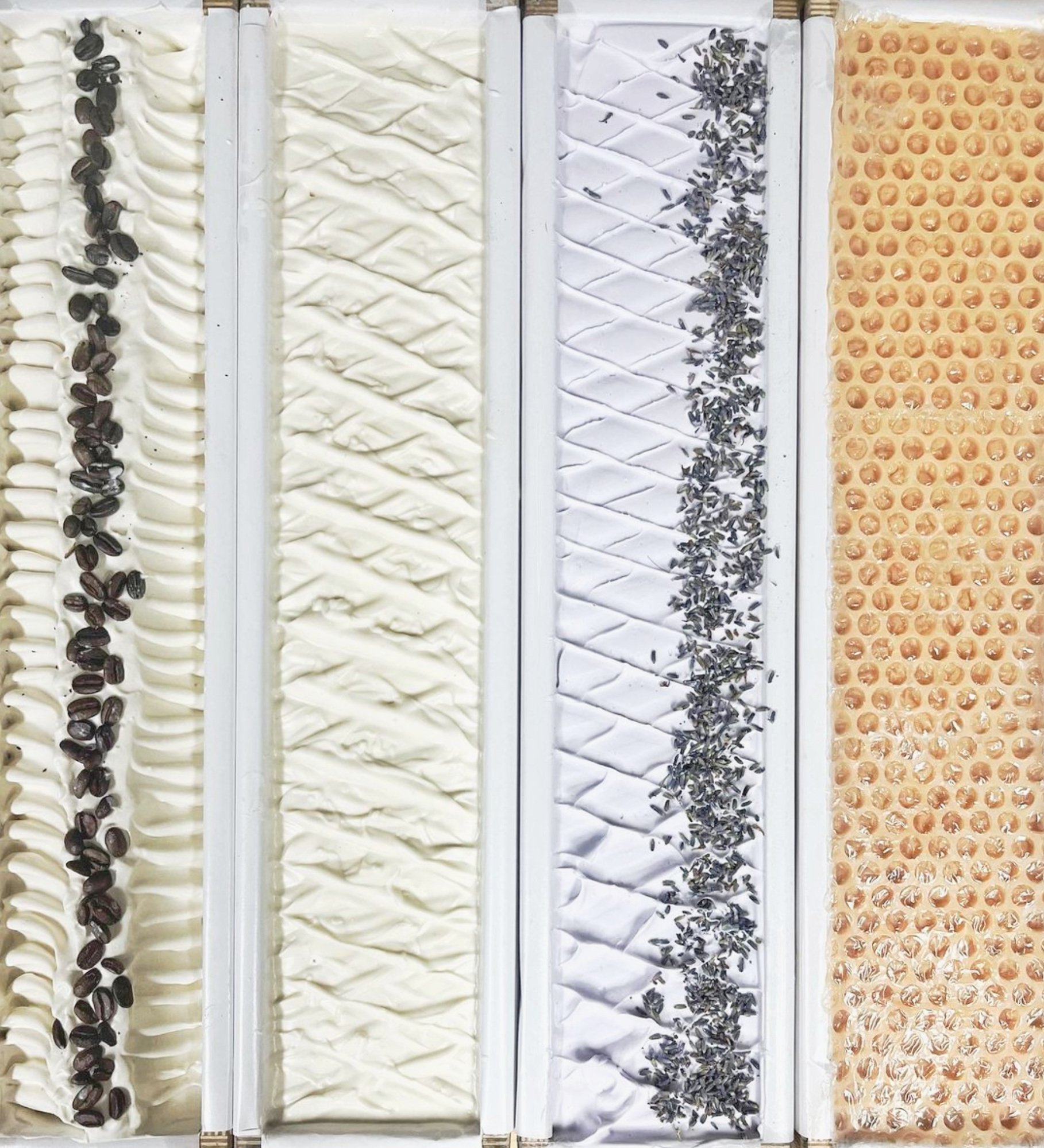 4 different soap loaves: 1 white with coffee beans, one plain, one light violate with dried laveder, one with a honeycomb pattern and tan