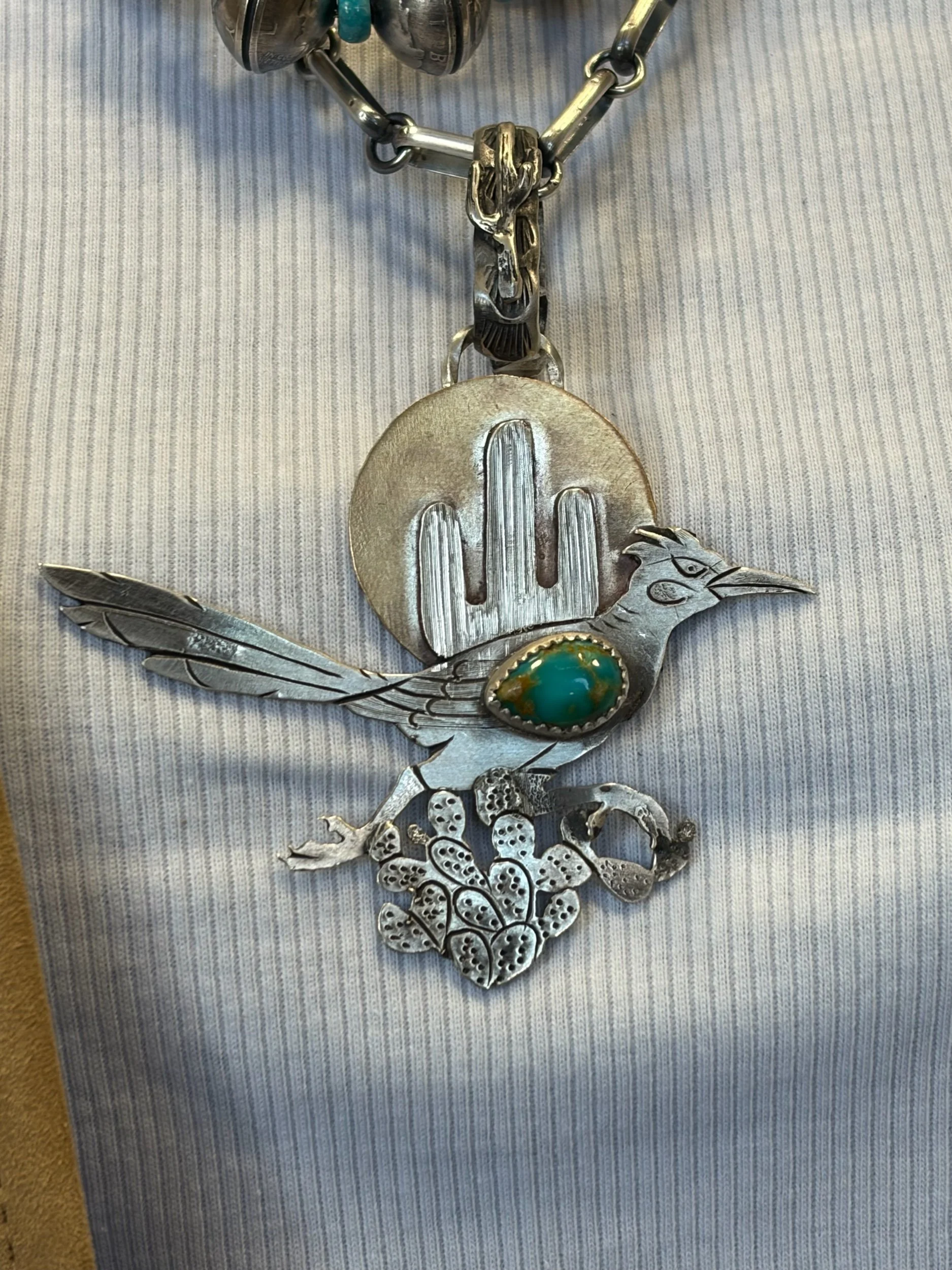 The Tol Eo (Snake Turkey) Pendant 

Handcrafted with intention and character, this one-of-a-kind pendant captures the spirit of the Southwest. Featuring a detailed roadrunner in motion, this piece is brought to life with hand-engraved textures and la