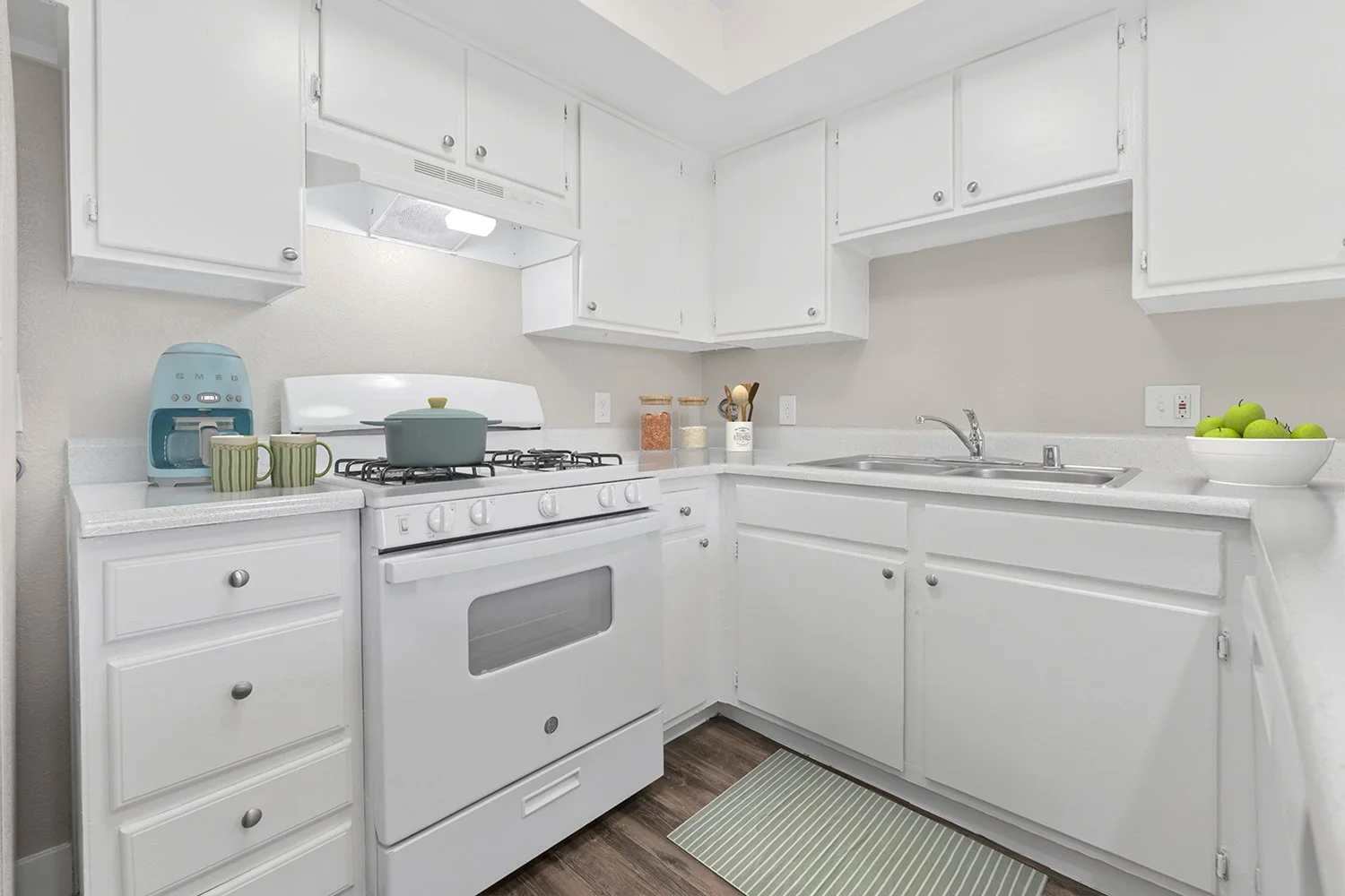 updated kitchen in Andorra 2 Bedroom apartment with wood-style plank flooring, white cabinetry, white appliances, and plenty of counter and storage space. 