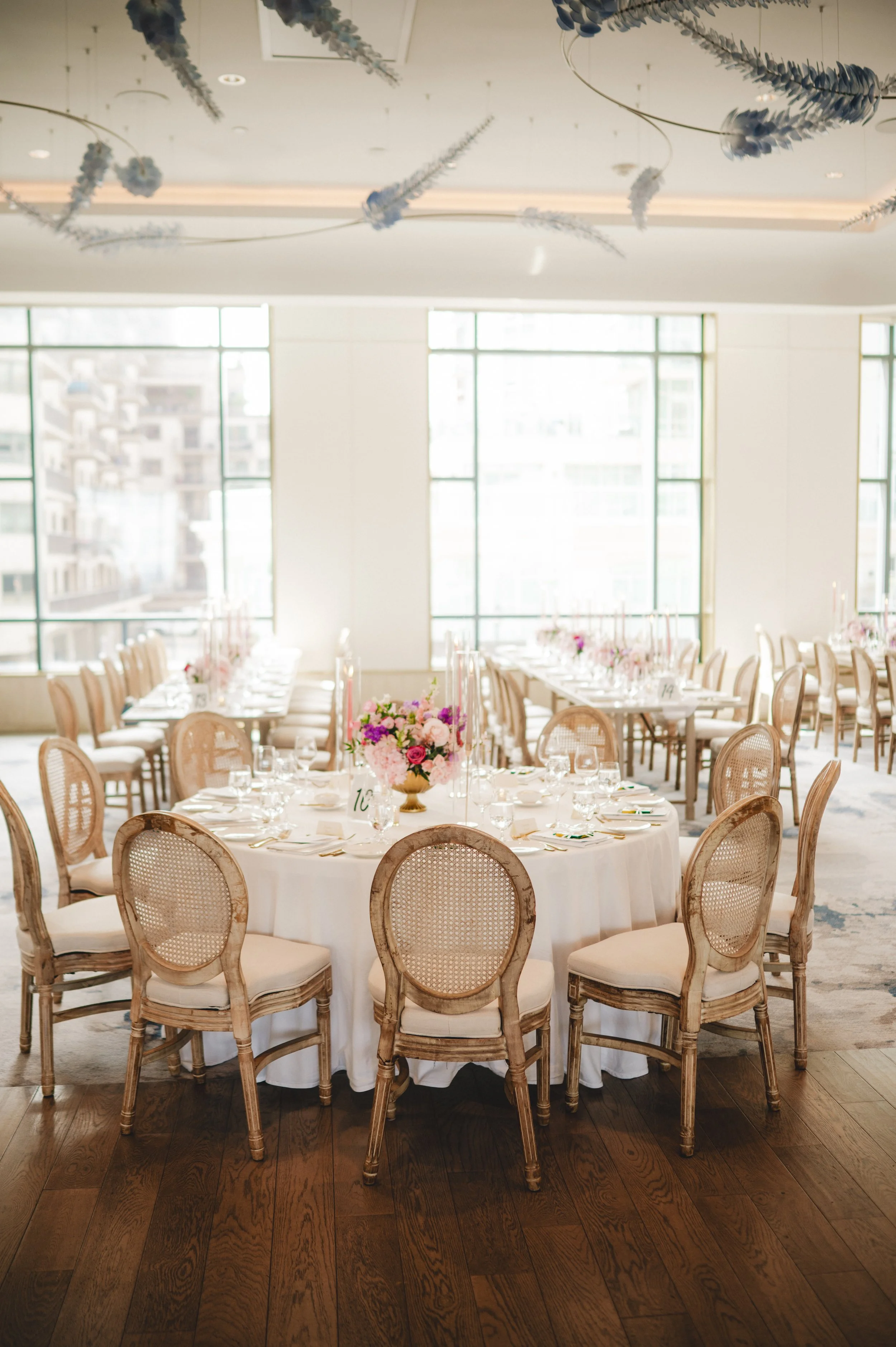 Pink and purple floral centrepieces with gold compotes and taper candles at a Pearle Hotel and Spa wedding reception.