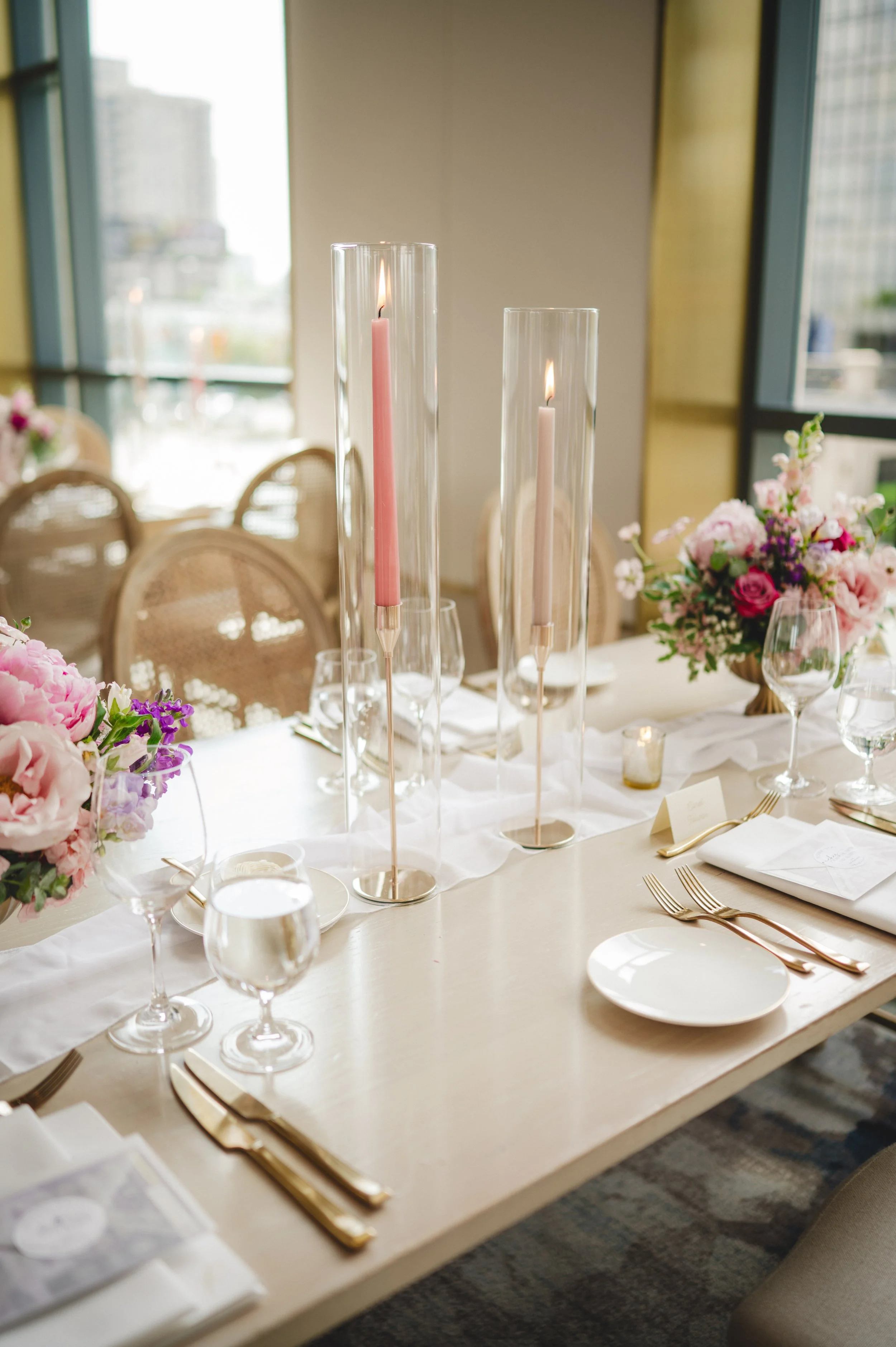 Pink and purple floral centrepieces with gold compotes and taper candles at a Pearle Hotel and Spa wedding reception.