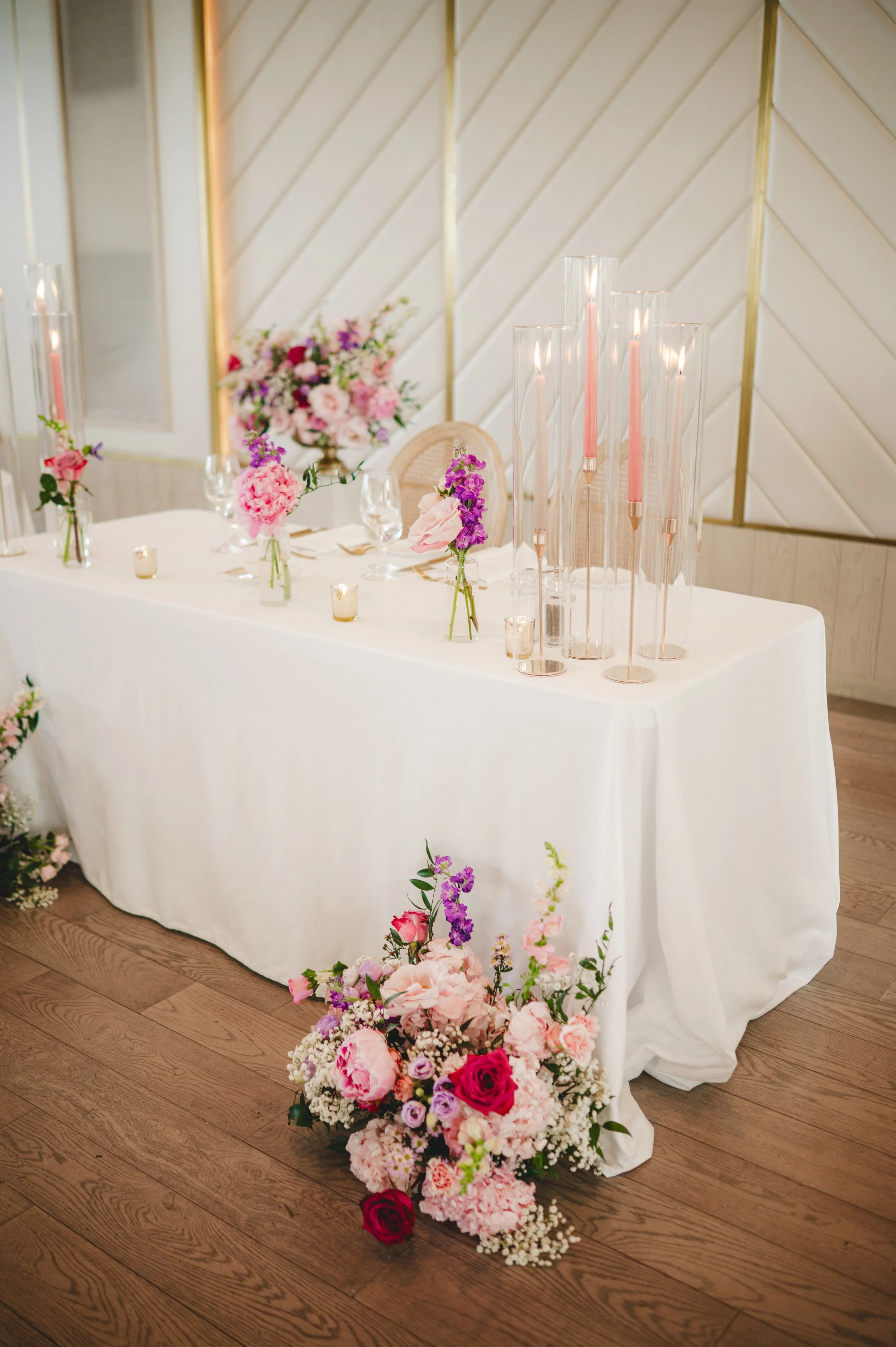 Pink and Purple sweetheart table flowers and taper candles at a wedding at the Pearle Hotel and Spa