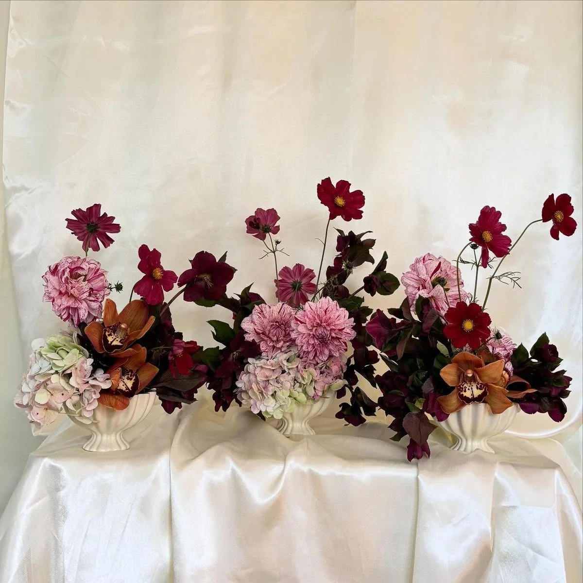 A floral arrangement designed with burgundy cosmos, pink spotted dahlias, burgundy hellebores and brown cymbidium orchids. Hamilton Wedding Flowers