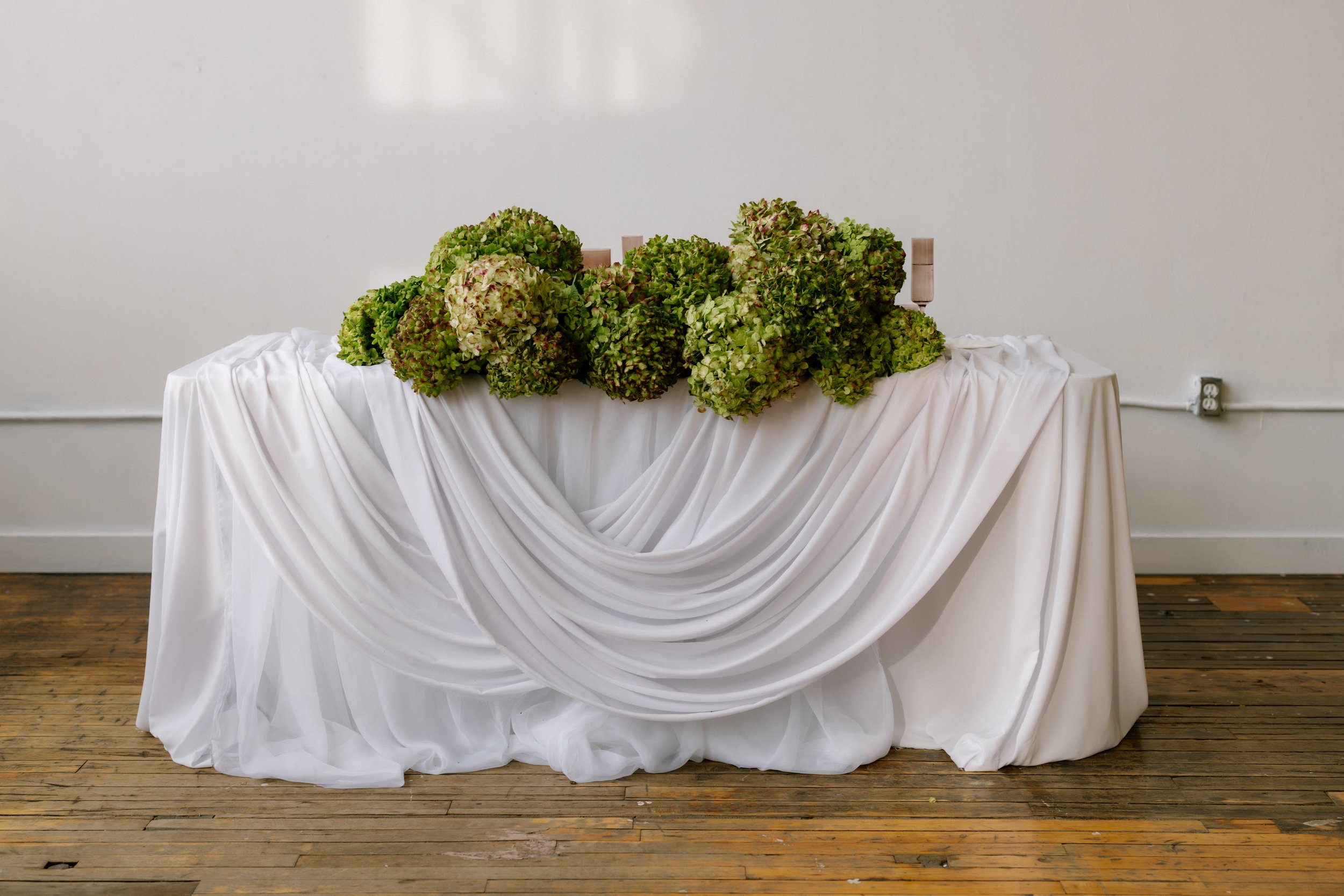 A wedding sweetheart table with green hydrangeas. Toronto Wedding Florist