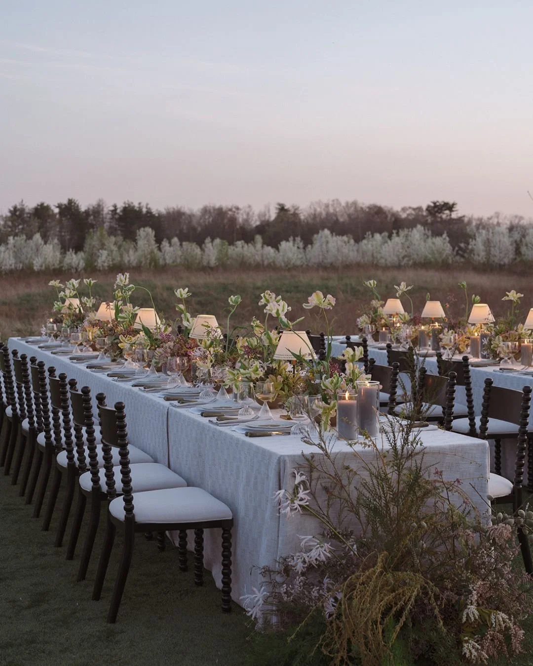 A modern wedding reception at dusk, with modern, whimiscal florals and table lamps. Toronto flower pricing