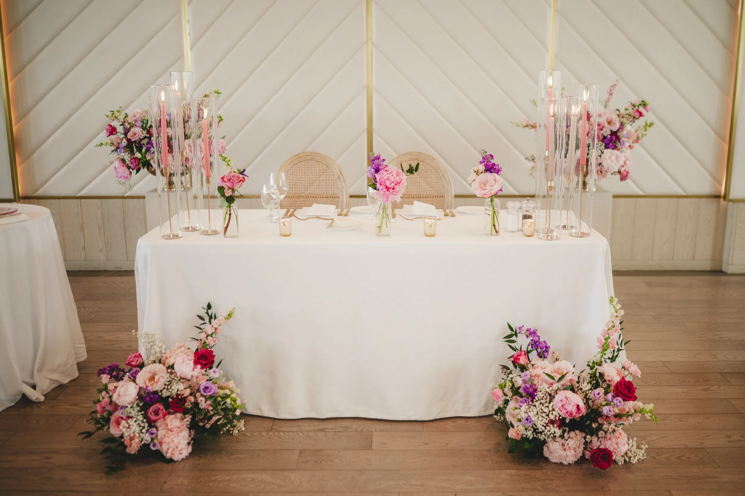 Pink and Purple sweetheart table flowers and taper candles at a wedding at the Pearle Hotel and Spa