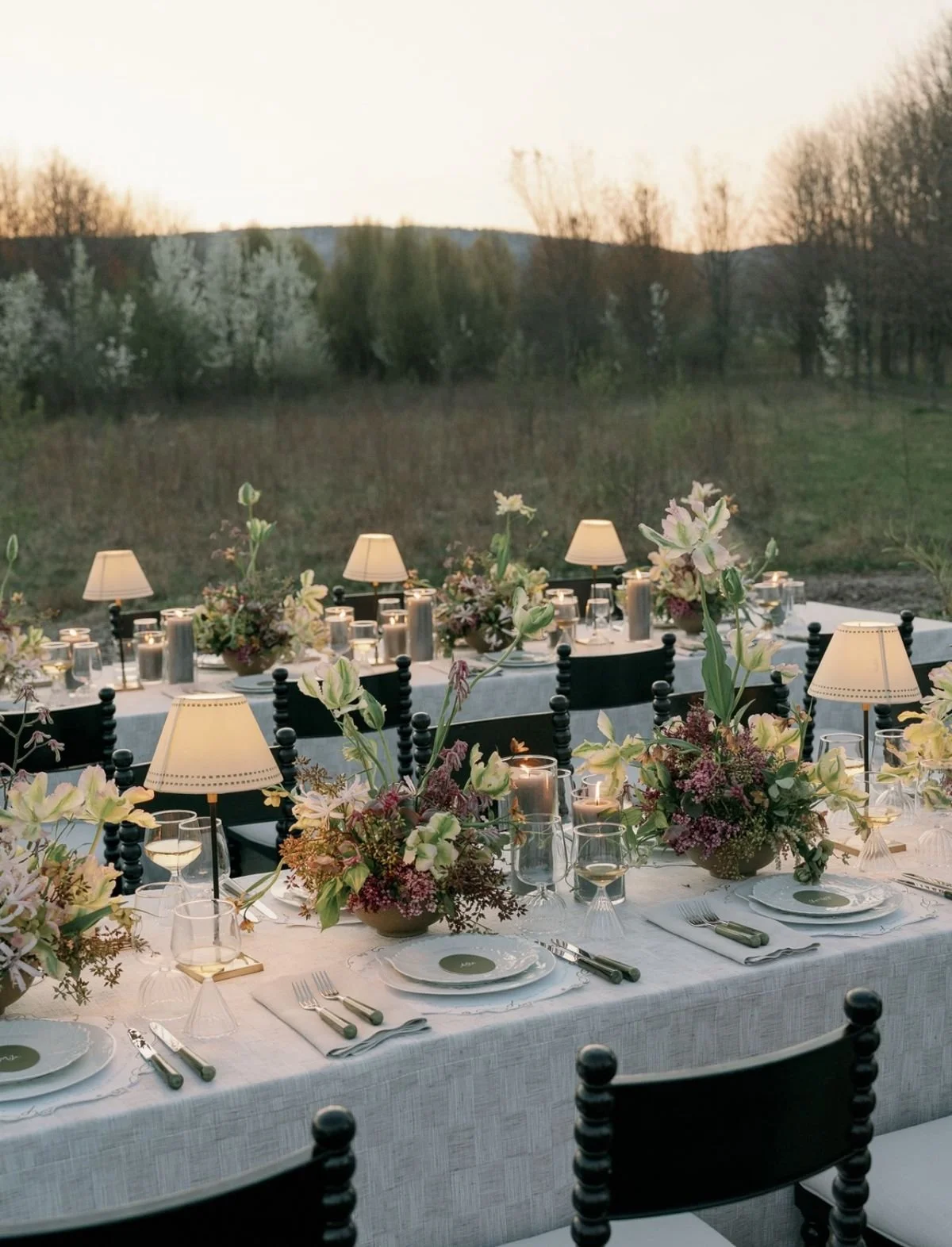 A modern wedding reception at dusk, with modern, whimiscal florals and table lamps. Toronto flower pricing